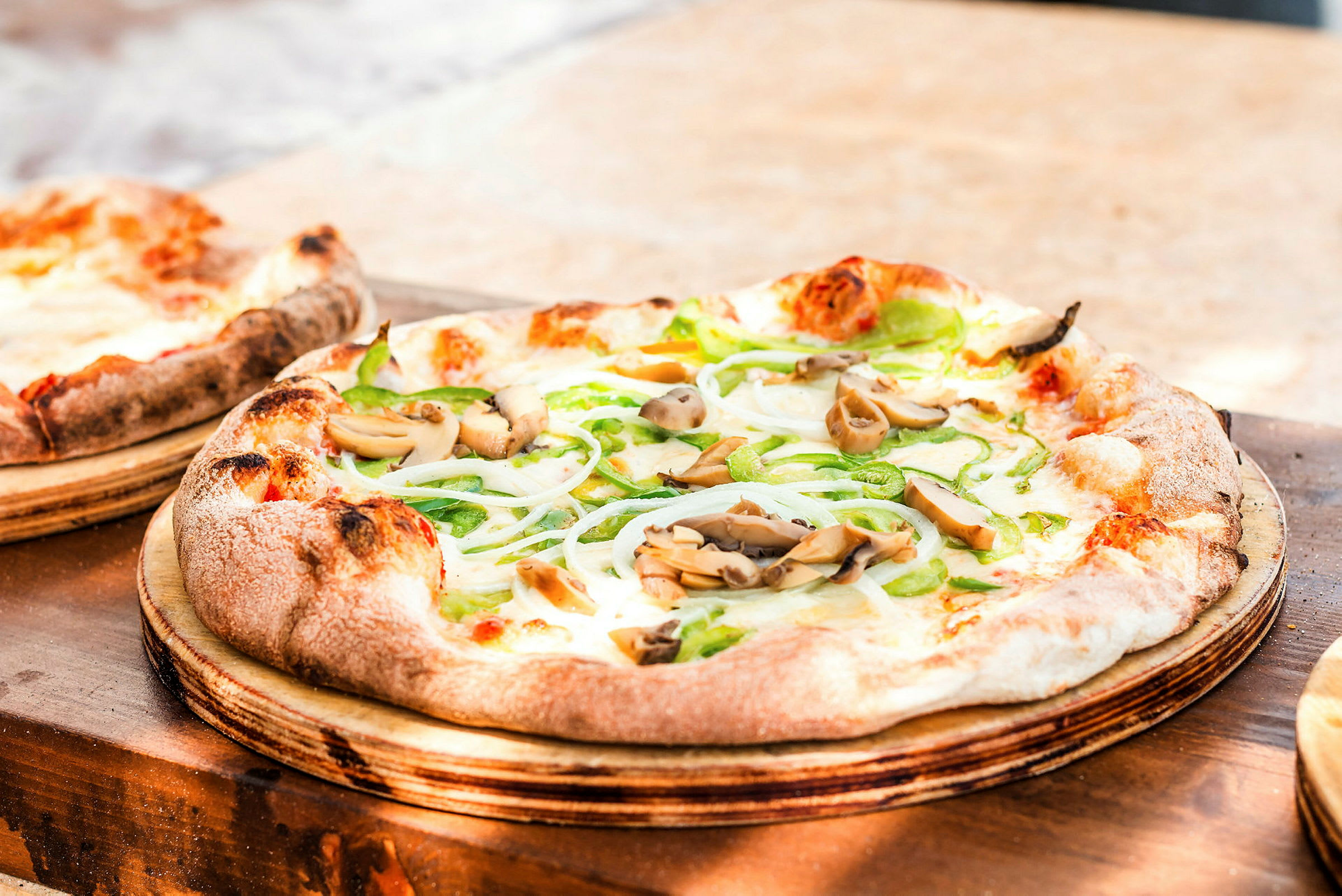 Et nærbillede af en pizza med grøntsager og svampe, serveret på en træplade. (AI-genereret tekst)