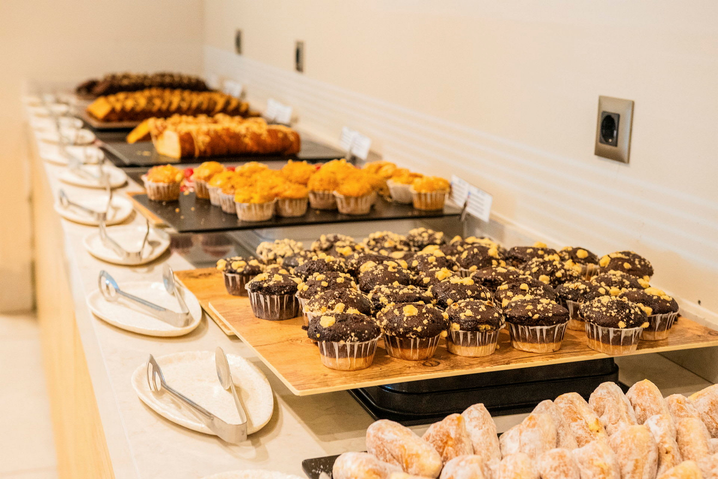 Et bord med forskellige typer bagværk, inklusive chokolademuffins og kager, arrangeret på fade. (AI-genereret tekst)