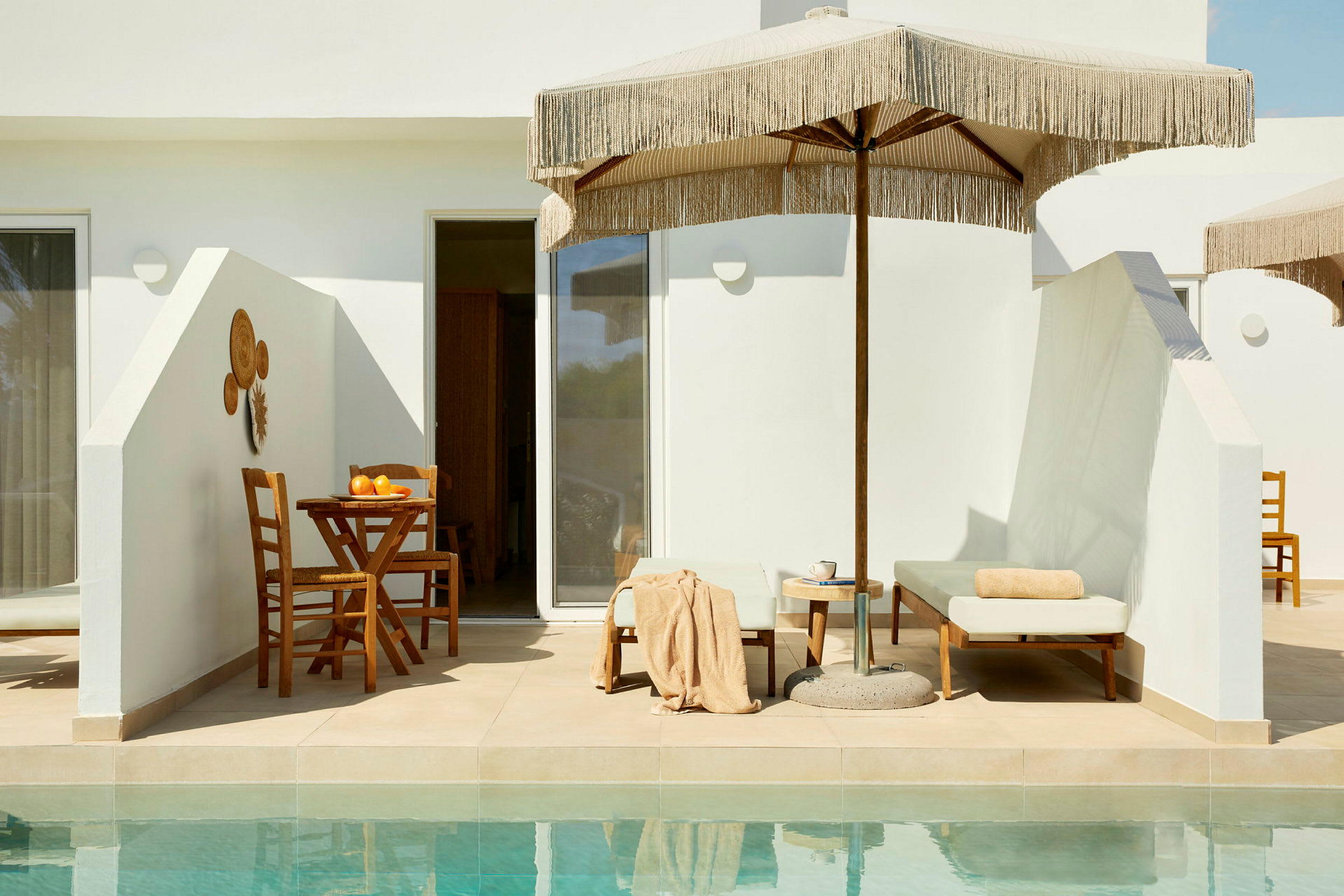 Udendørsområde med solseng, parasol og spisebord ved kanten af en pool. (AI-genereret tekst)