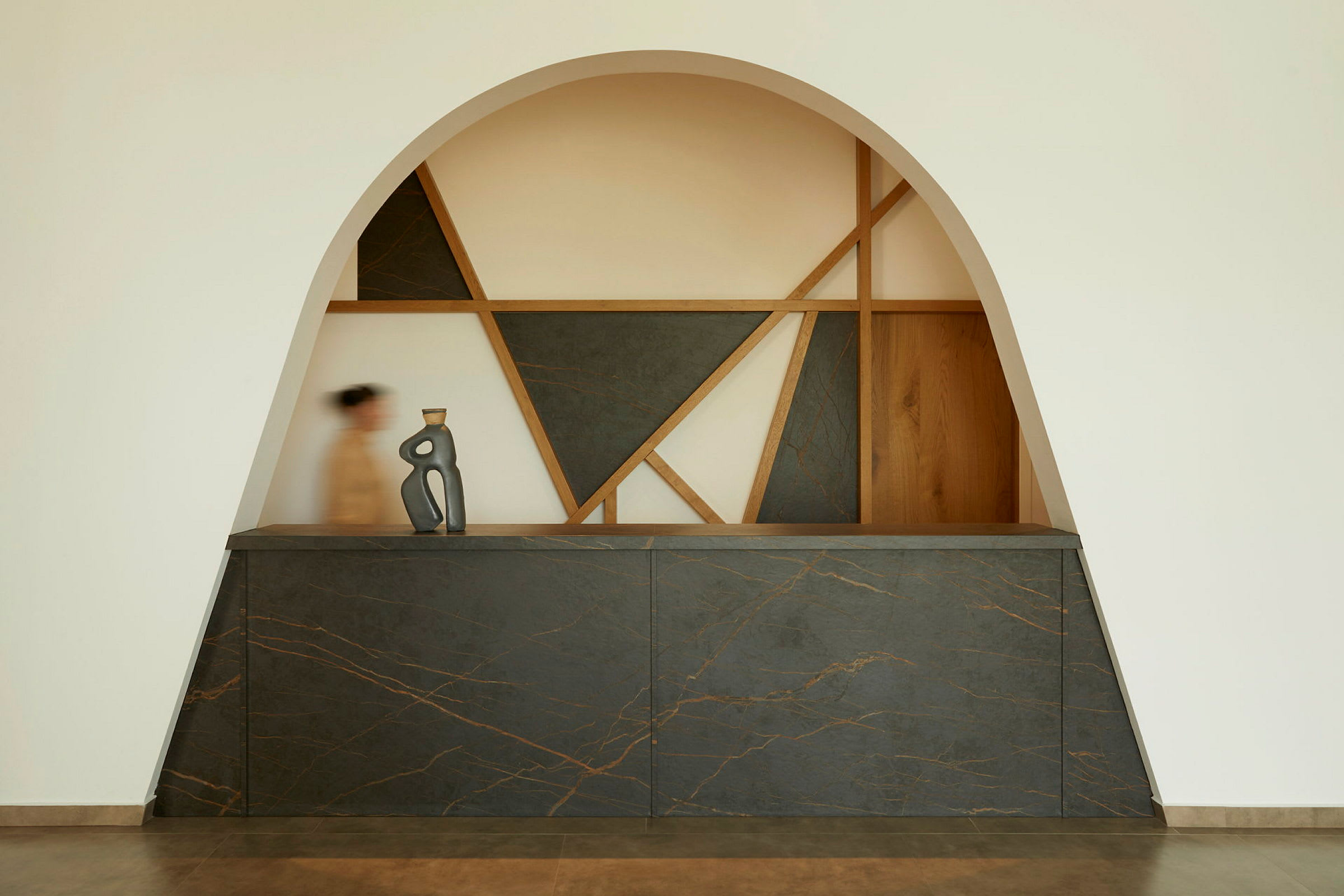 En reception med moderne design, geometriske former og en kunstnerisk skulptur på skranken. (AI-genereret tekst)