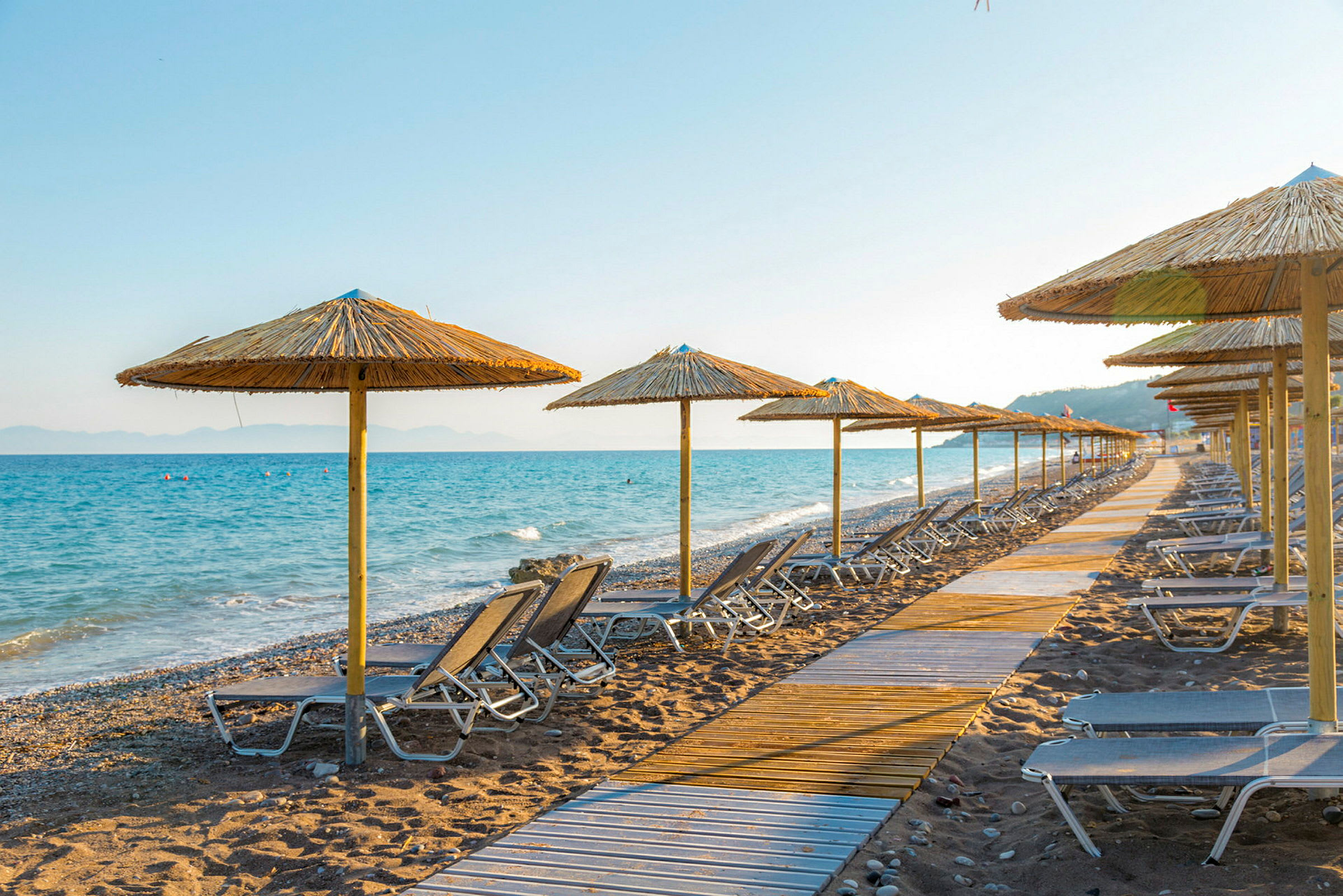 Strandstole og parasoller på en strand ved havet. (AI-genereret tekst)
