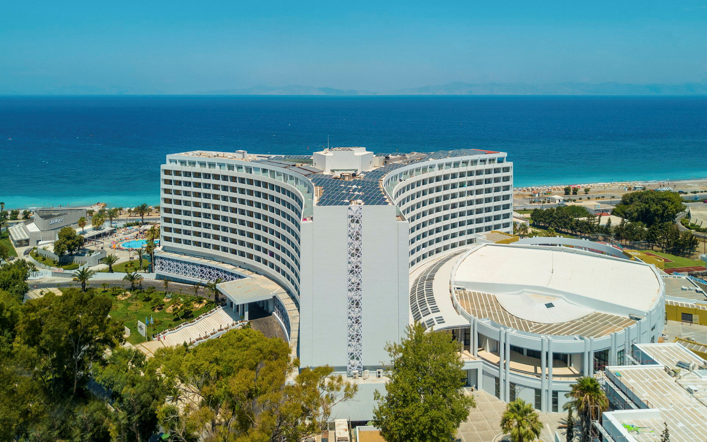 Hotellet med havet og stranden i baggrunden. (AI-genereret tekst)