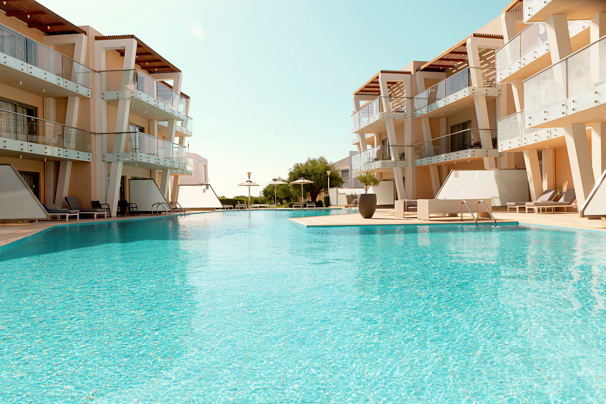 En swimmingpool omgivet af moderne bygninger med tilhørende altaner. (AI-genereret tekst)
