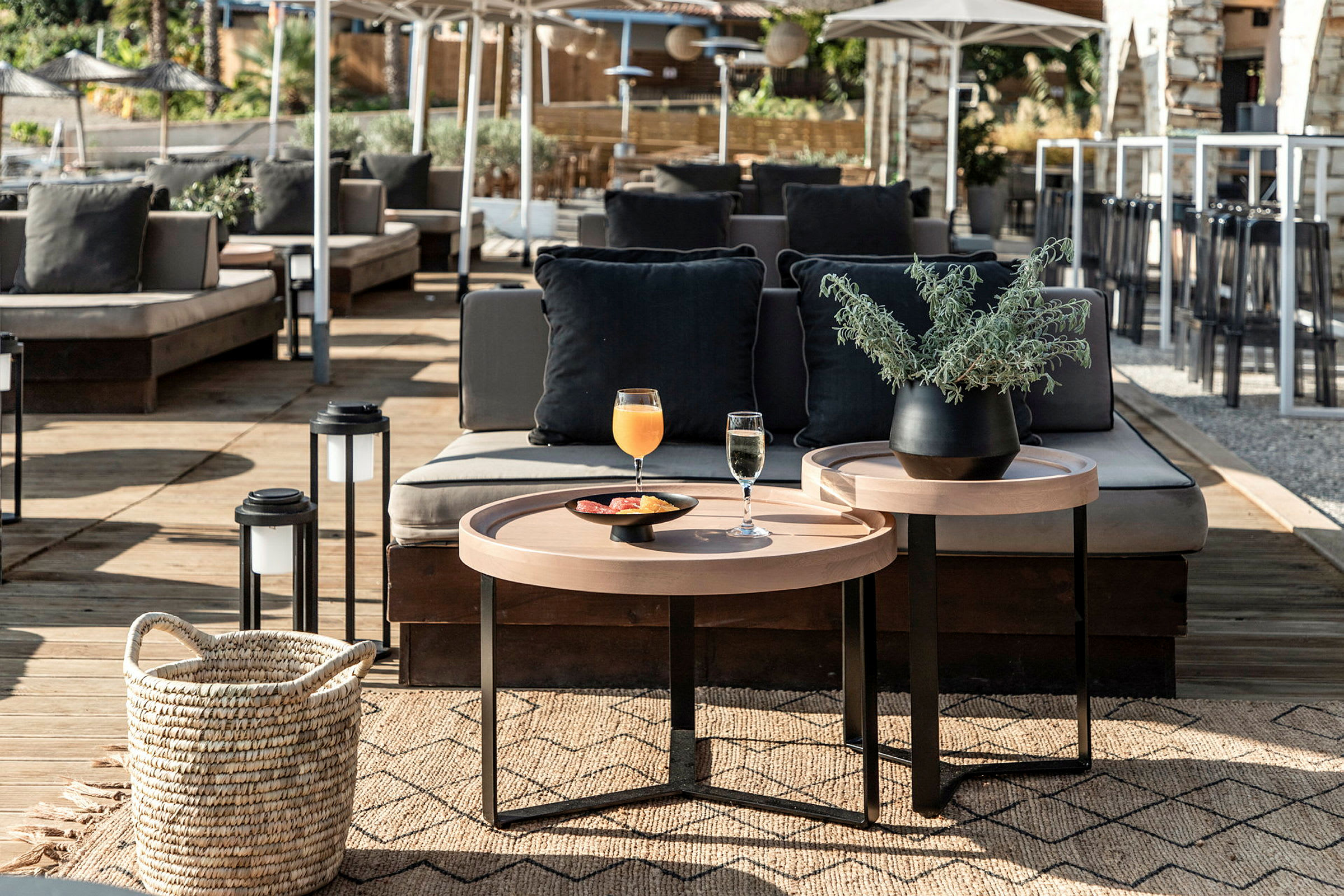 En udendørs terrasse med sofaer, et bord med drikkevarer og en plante i potte. (AI-genereret tekst)