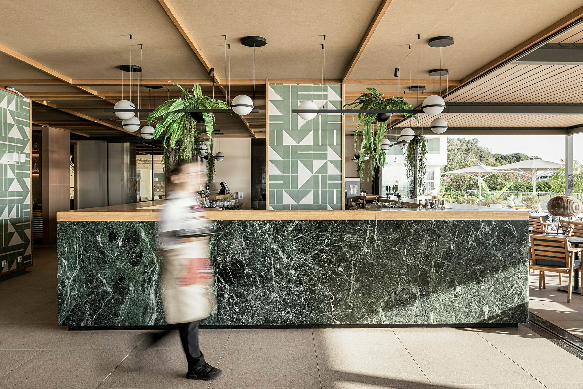 En moderne hotelbar med marmordisk og grønne planteudsmykninger. (AI-genereret tekst)