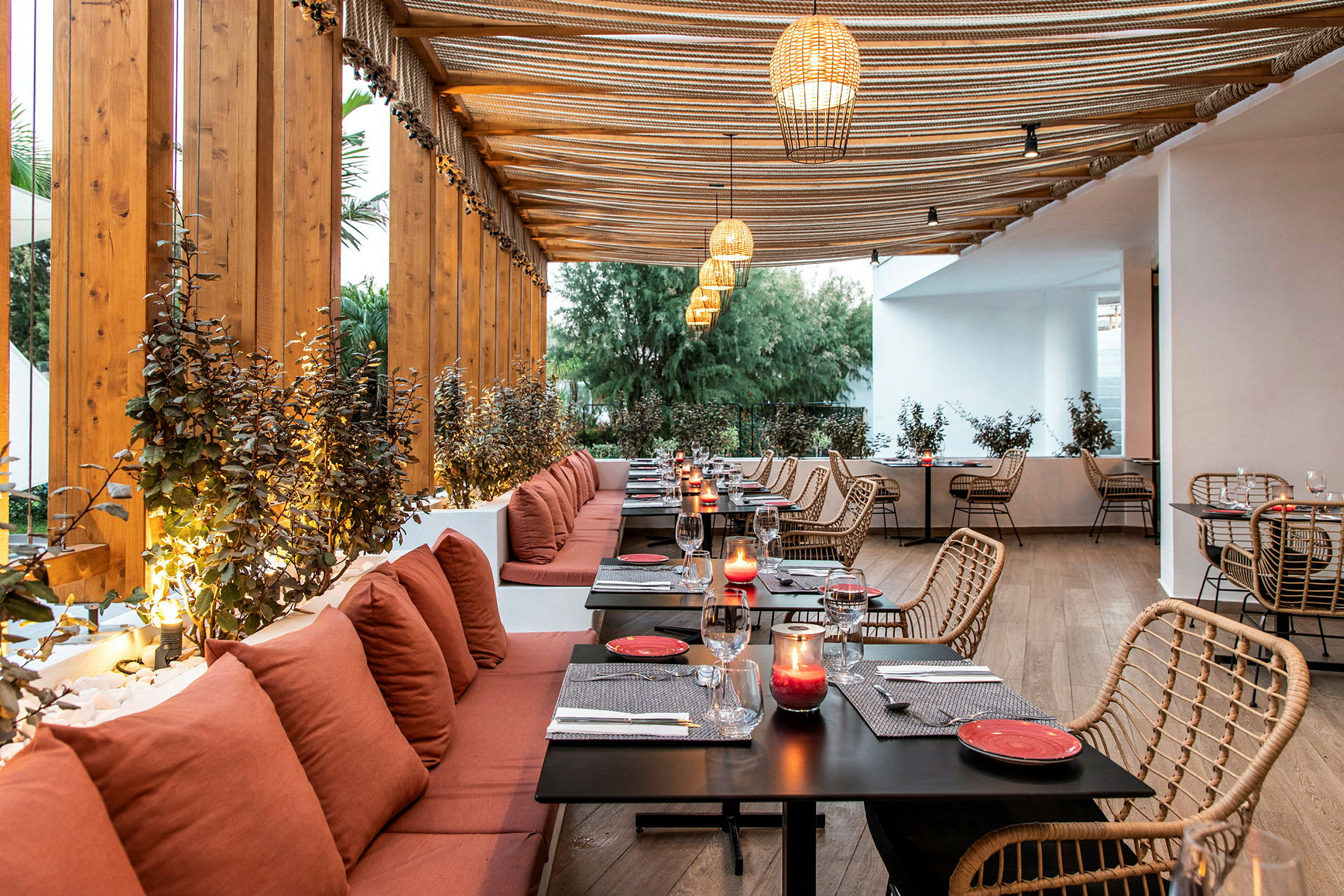 Restaurant med træbeklædt interiør, røde puder ved siddepladser og borde med dekorationer. (AI-genereret tekst)