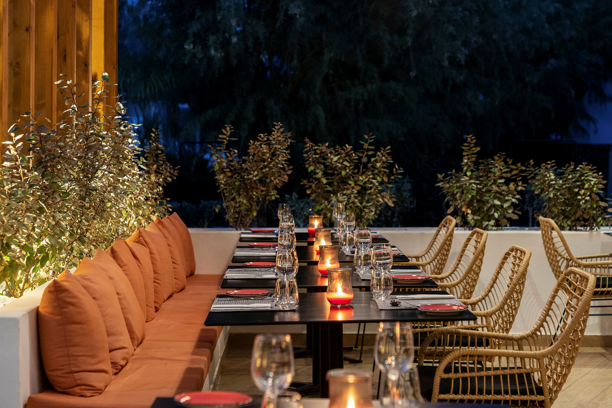 En restaurant med dækkede borde og tændte lys på en udendørs terrasse. (AI-genereret tekst)