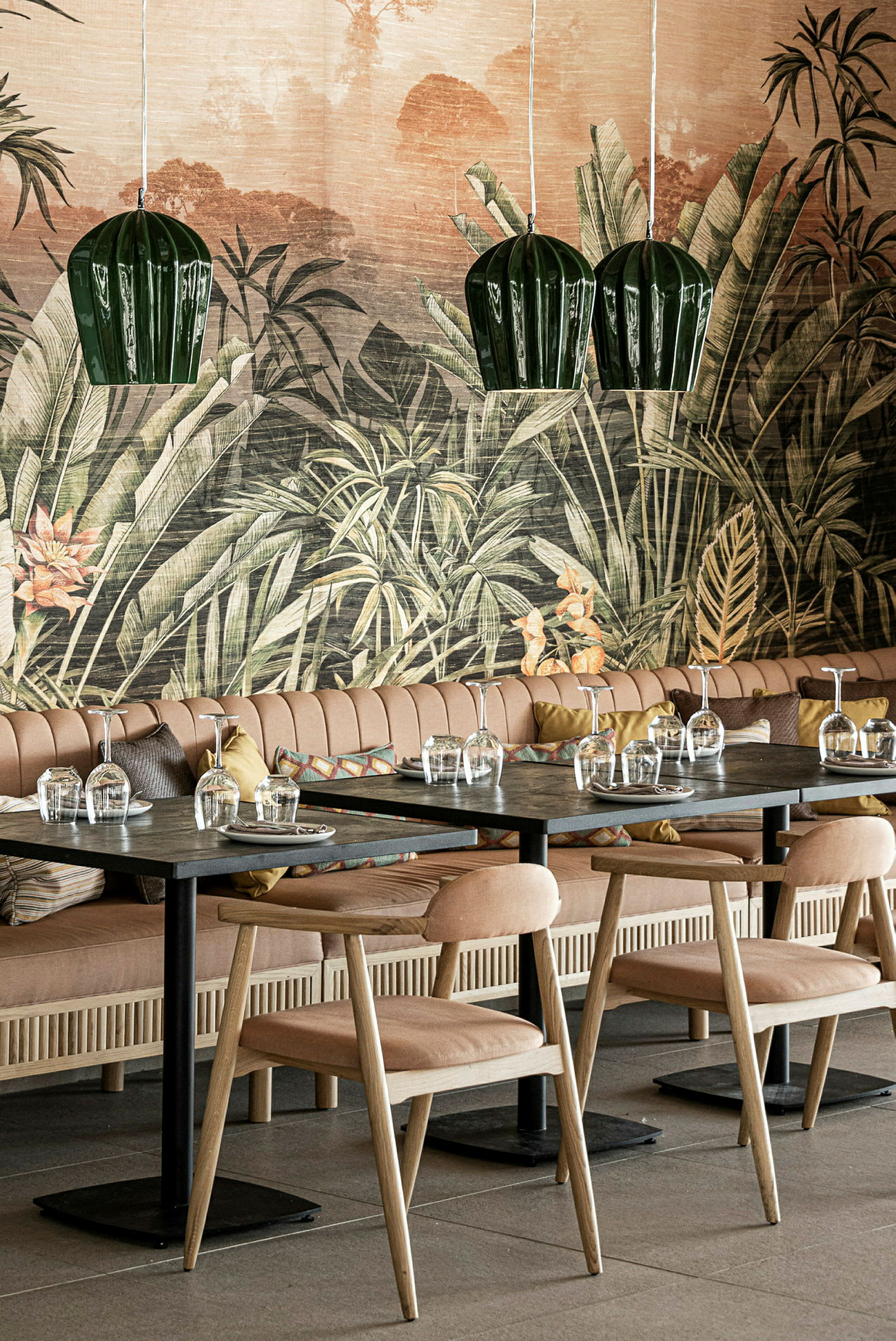 En restaurant med borde og stole foran en væg med tropisk motiv. (AI-genereret tekst)