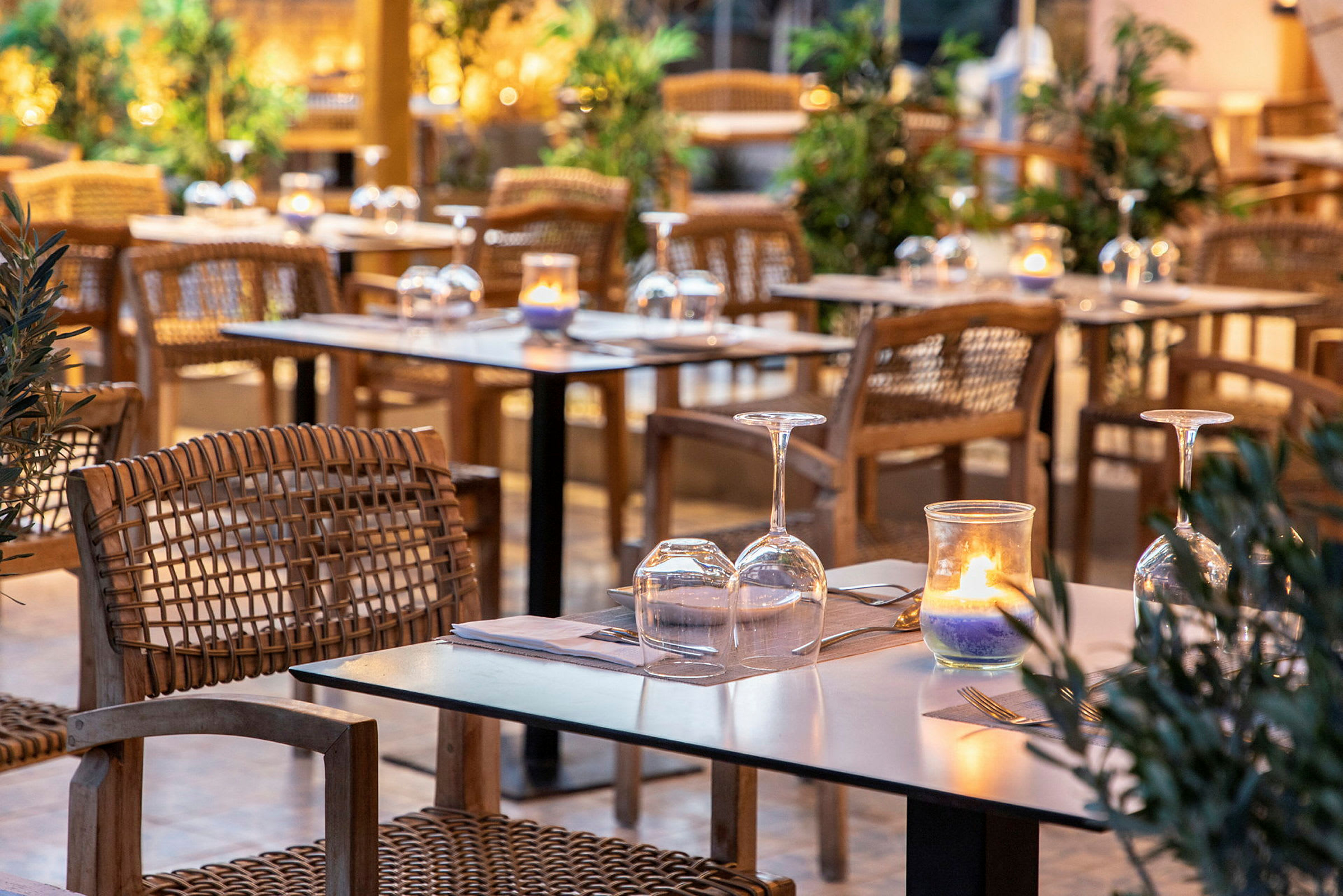 En udendørsrestaurant med dækkede borde, vinglas og lys. (AI-genereret tekst)