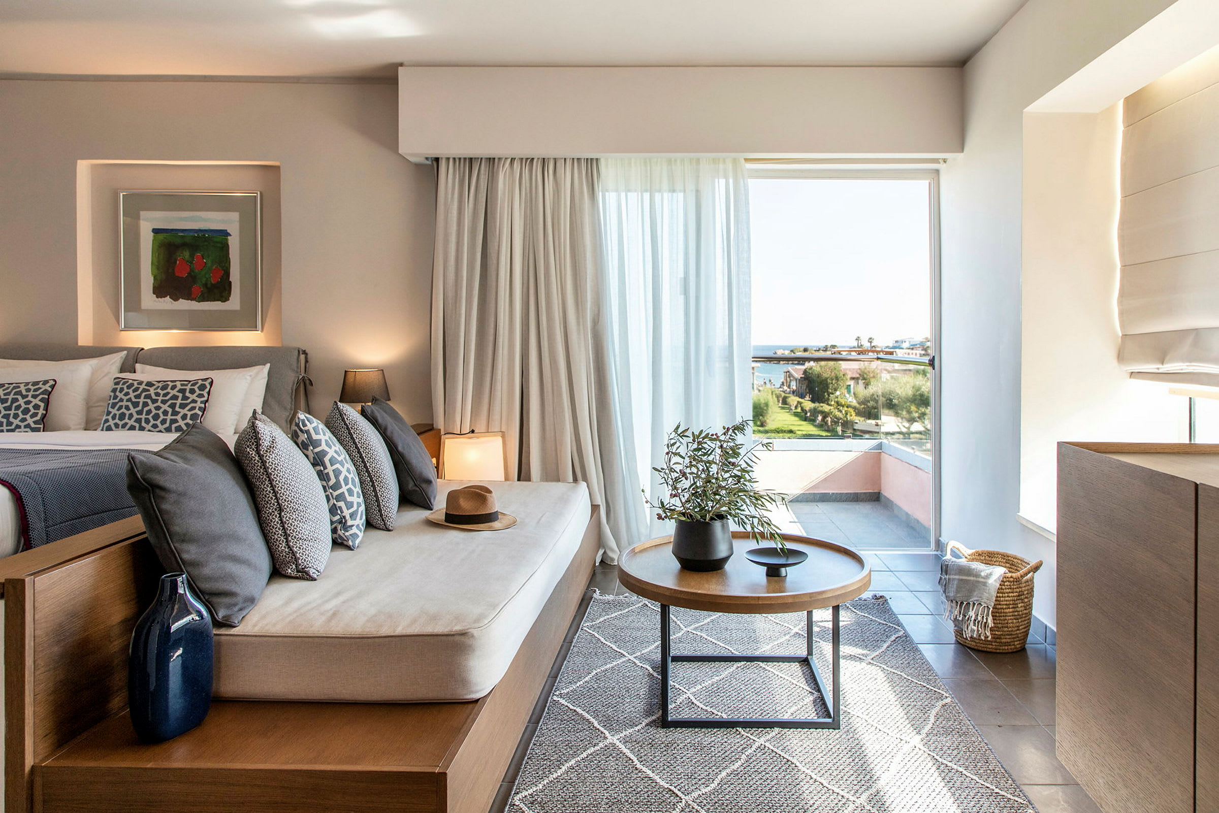 Billede af et moderne hotelværelse med siddeplads og udsigt over landskabet gennem et stort vindue. (AI-genereret tekst)