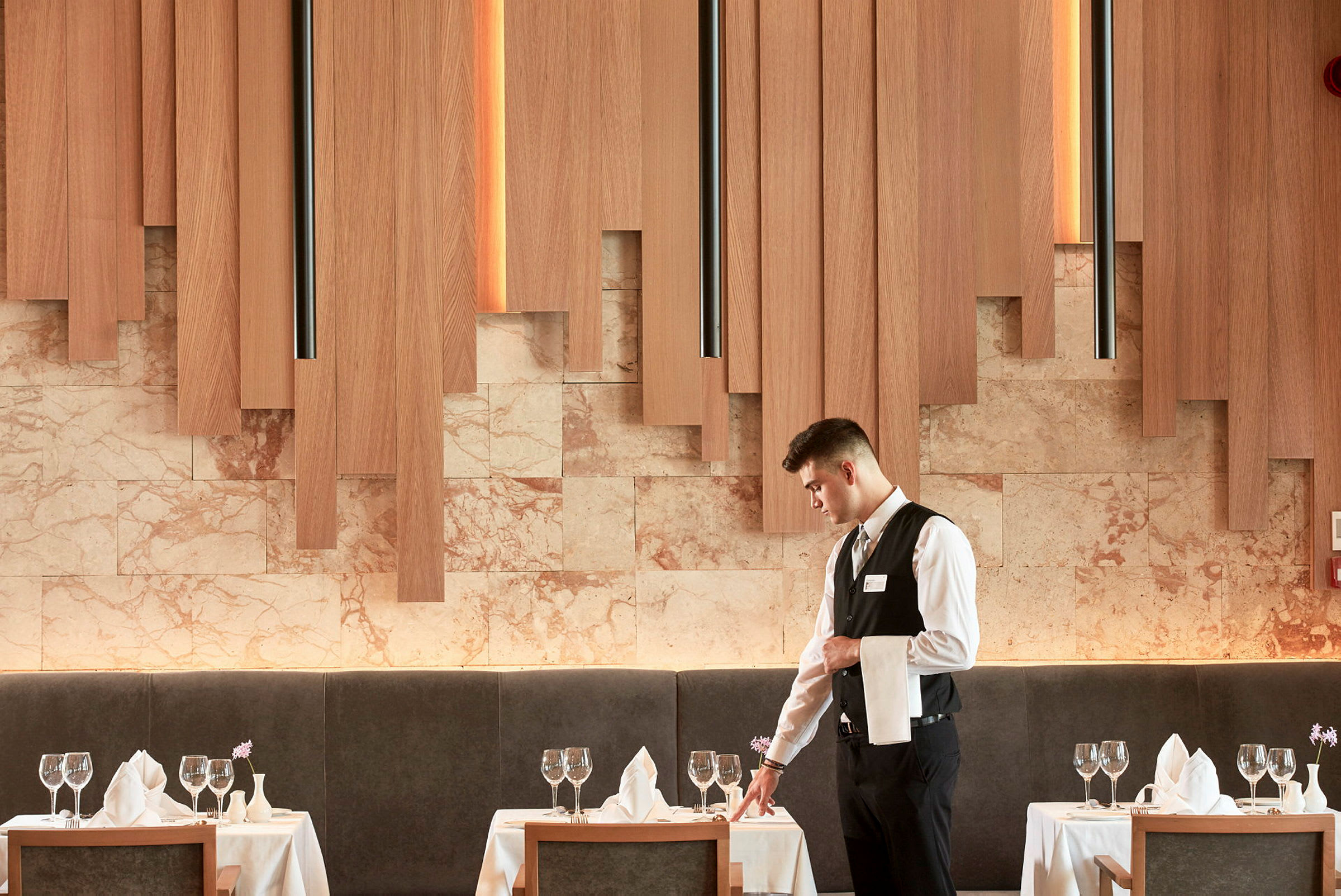 Et elegant restaurantmiljø med opdækkede borde, glas og servietter og træpaneler på væggene. (AI-genereret tekst)