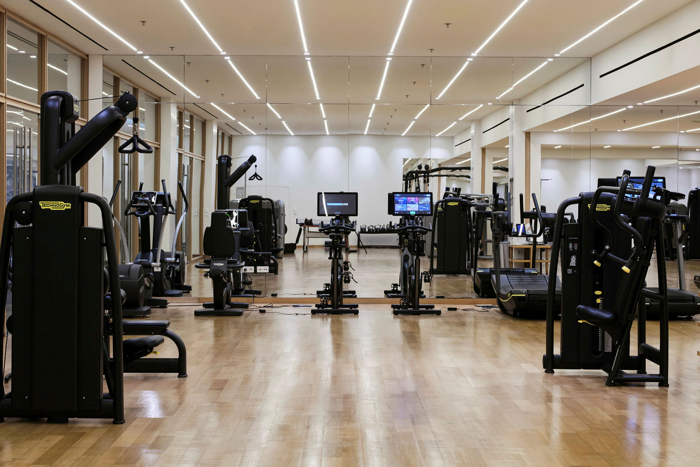 Fitnesscenter med træningsmaskiner og spejl væg. (AI-genereret tekst)