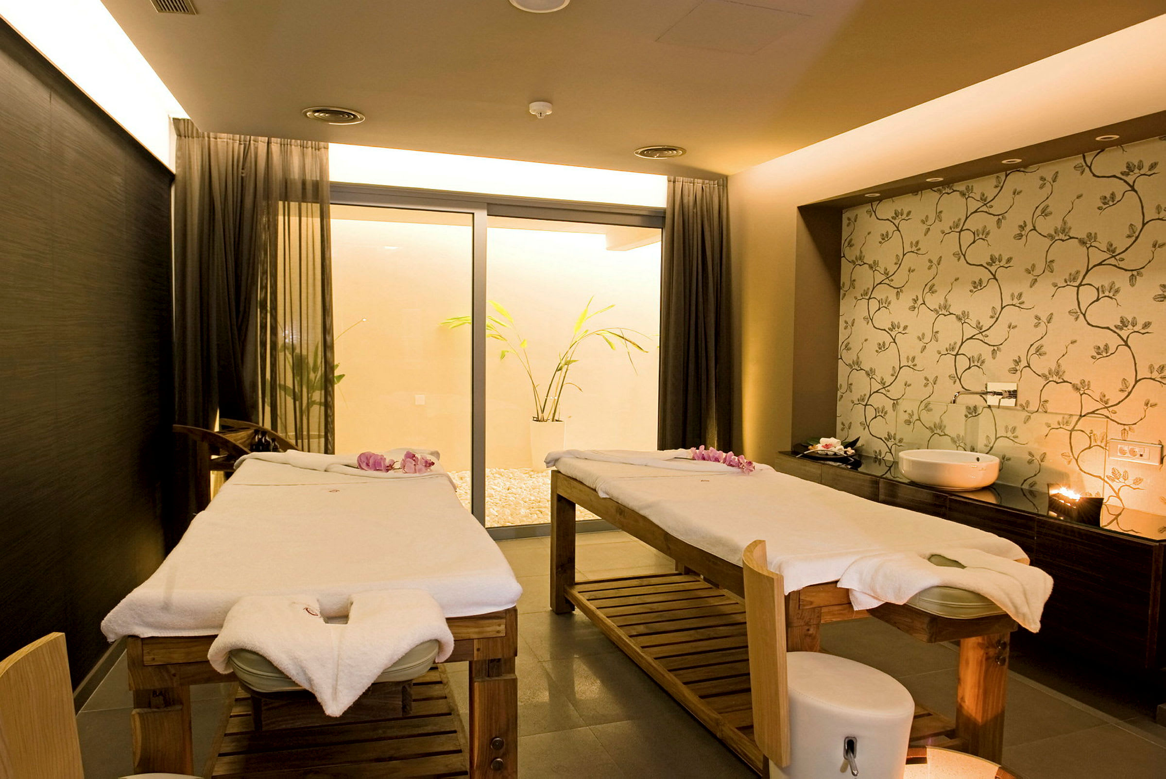To massagebænke på et spa, dekoreret med håndklæder og blomster. (AI-genereret tekst)