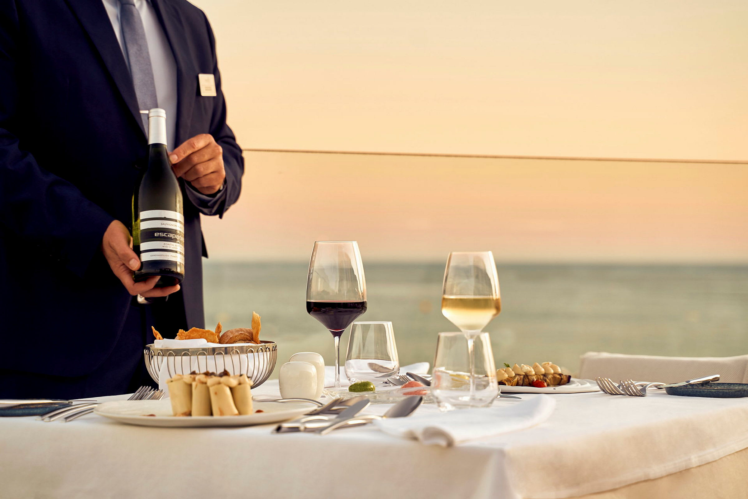 Restaurantbord med servering af mad og drikke ved solnedgang. (AI-genereret tekst)