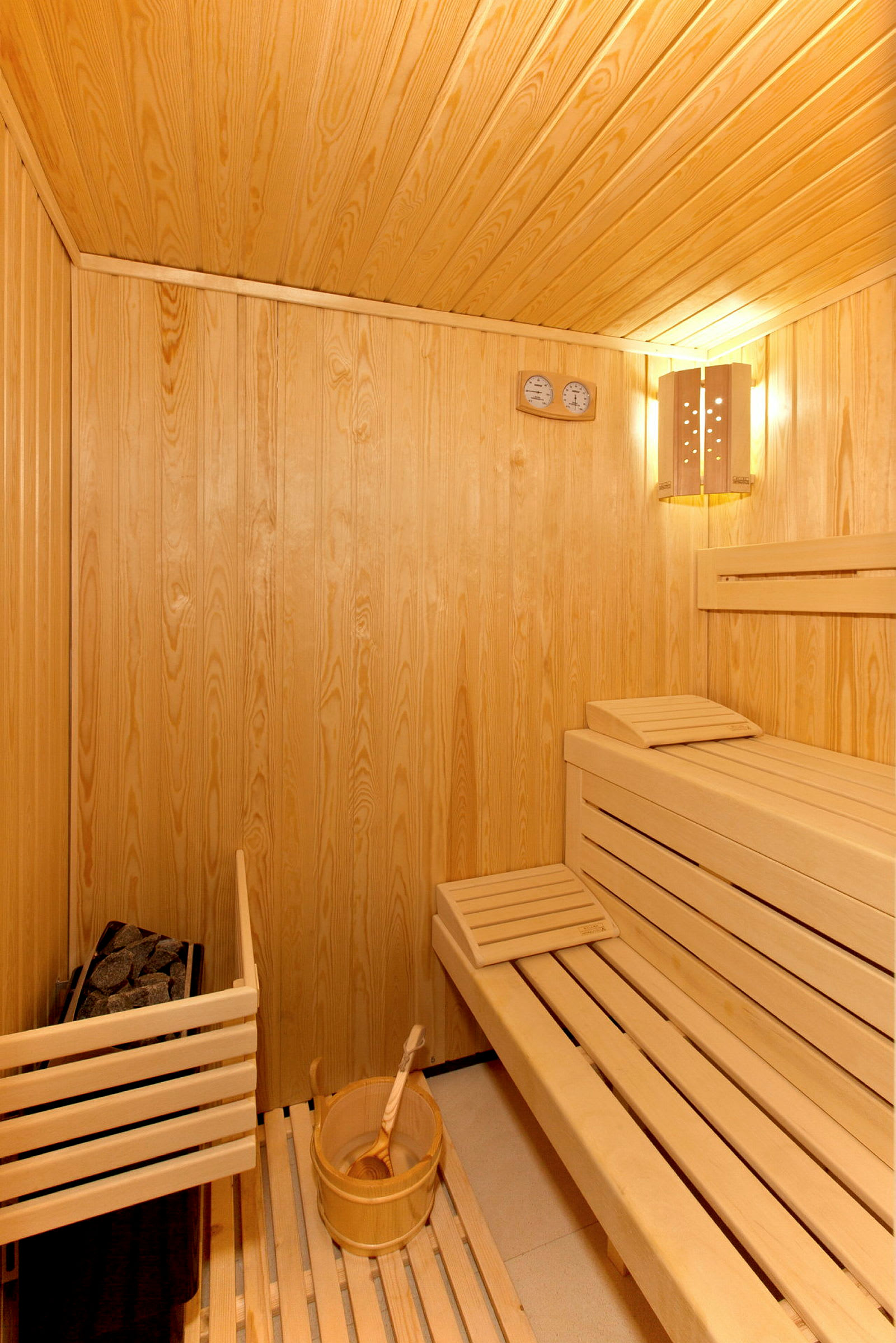 Billede af interiør i en sauna lavet af træ med siddebænke og en spand med en vandøse. (AI-genereret tekst)
