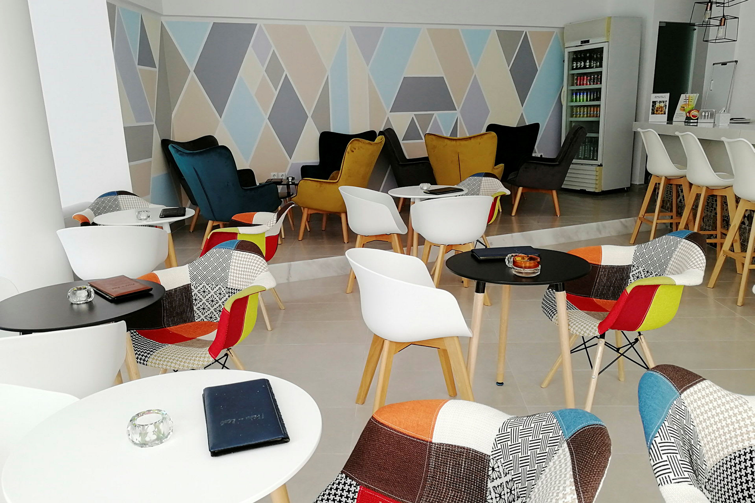 En moderne lounge med farverige stole og geometriske mønstre på væggen. (AI-genereret tekst)