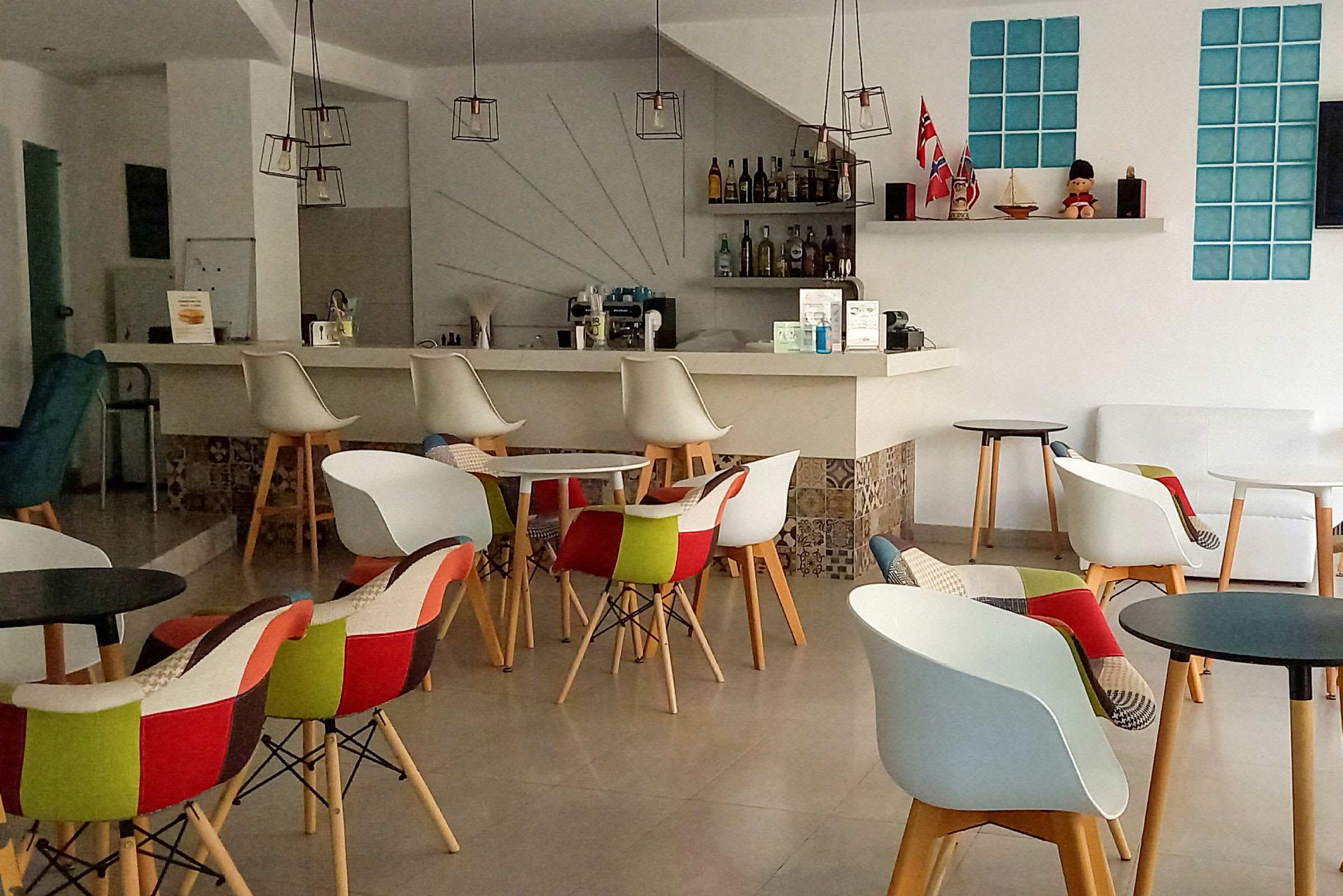 Interiør af en moderne kaffebar med farverige stole og små borde. (AI-genereret tekst)