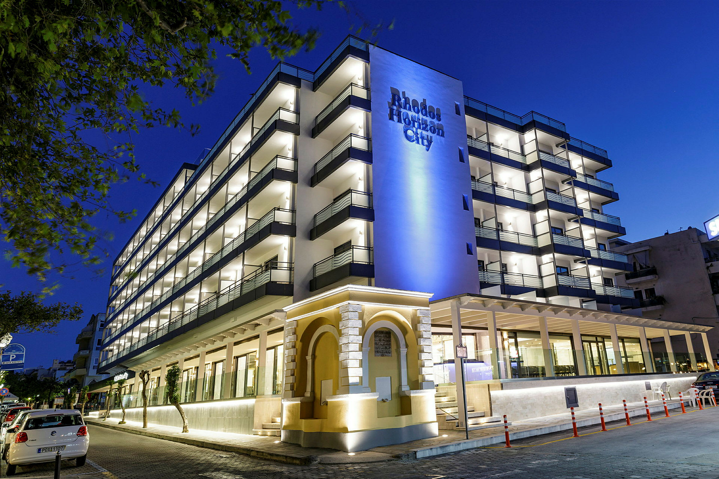 Hotelbygning med flere etager og oplyst facade om aftenen. (AI-genereret tekst)