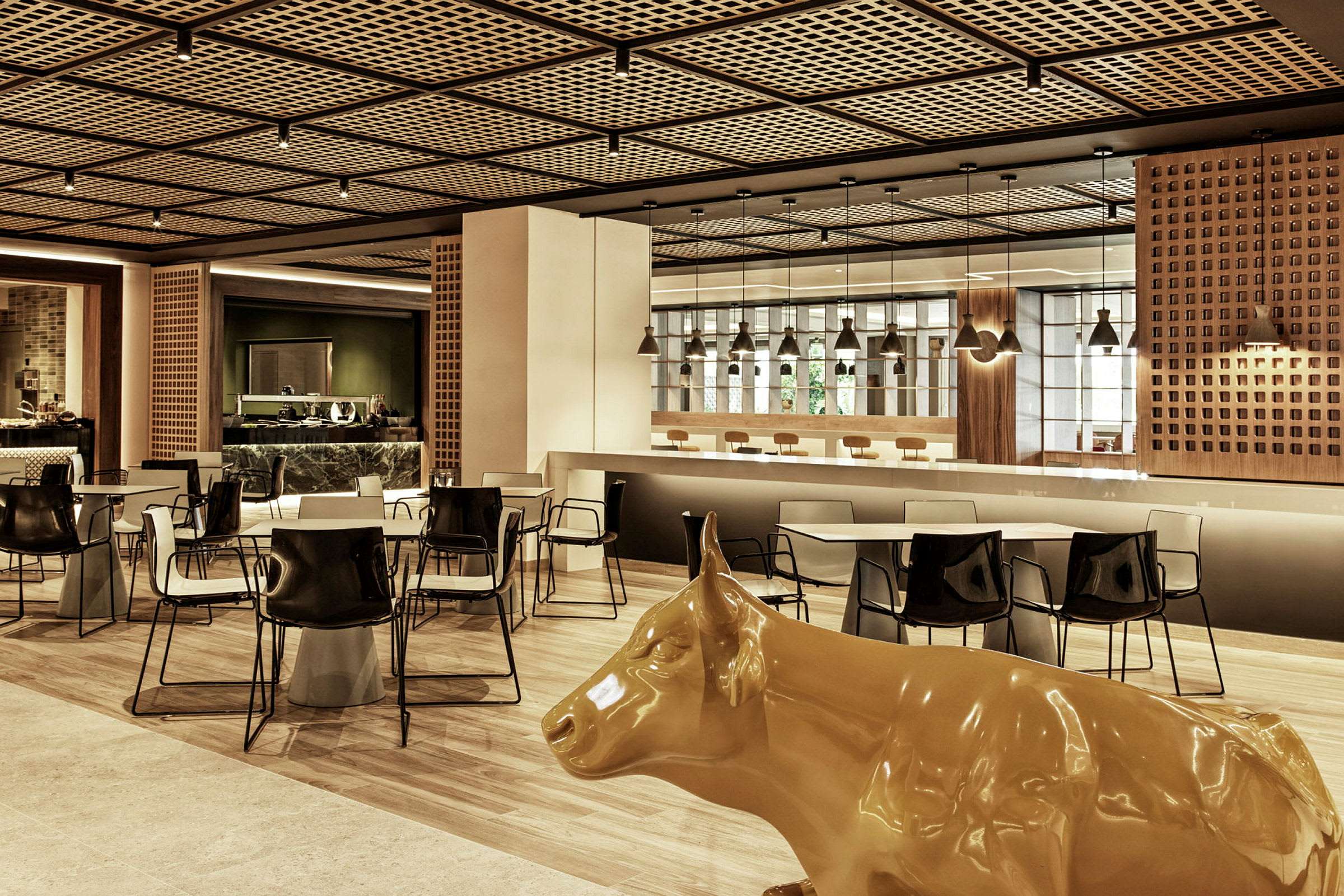 En moderne restaurant med borde, stole og en gul statue af en ko. (AI-genereret tekst)