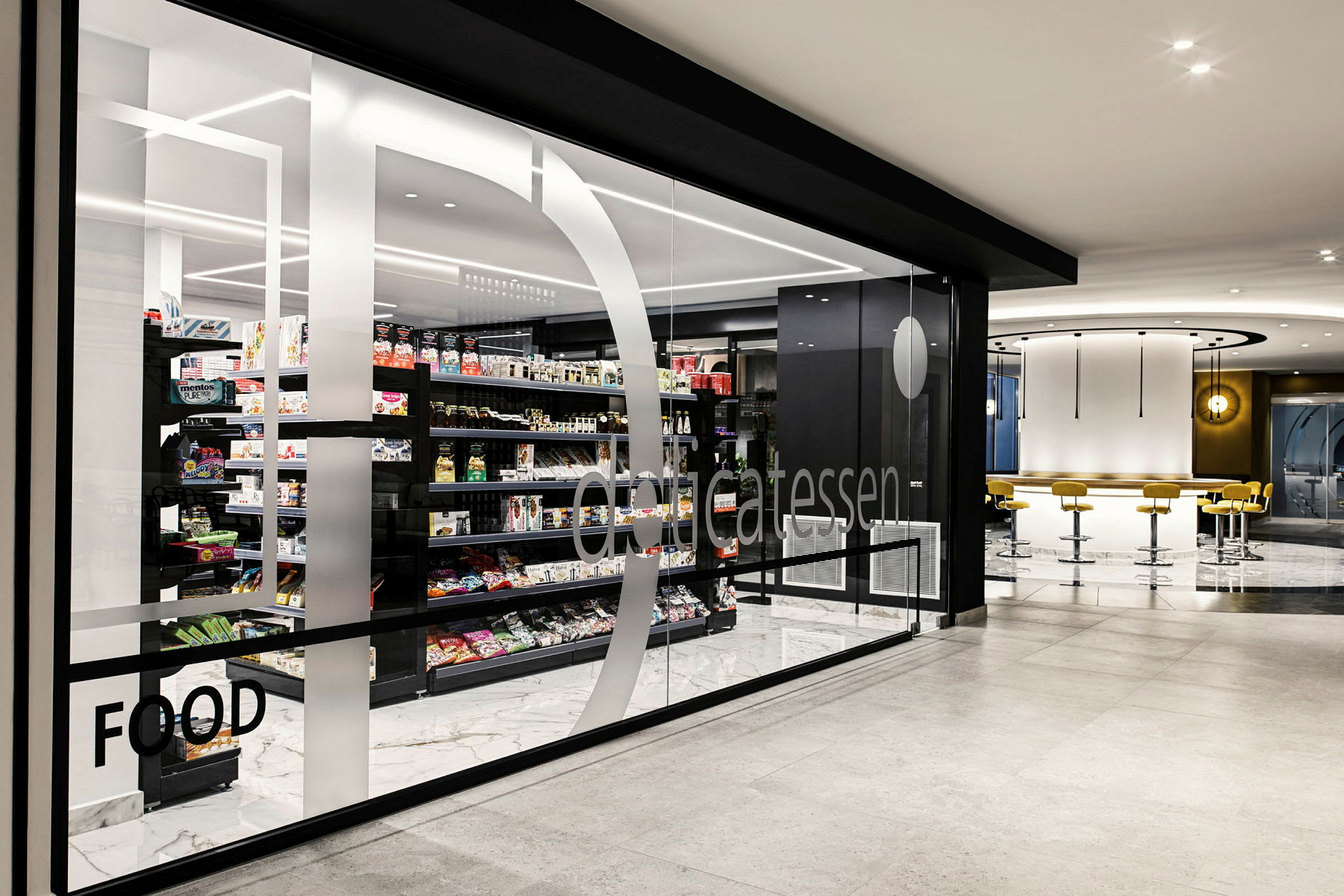 Interiør af en moderne fødevarebutik med glasvæg og varer på hylder. (AI-genereret tekst)