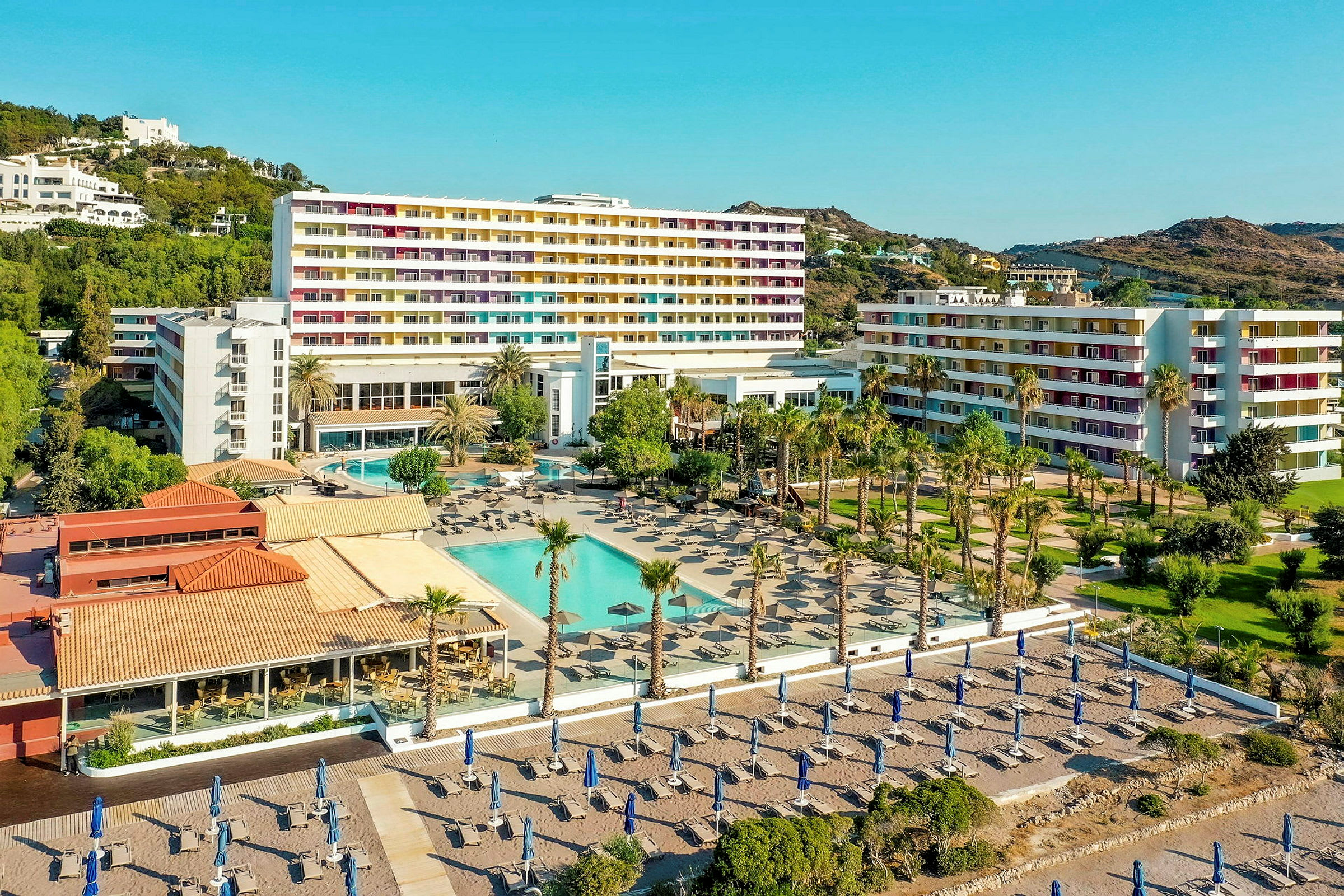 Hotelområde med pool, liggestole og sandstrand i baggrunden. (AI-genereret tekst)