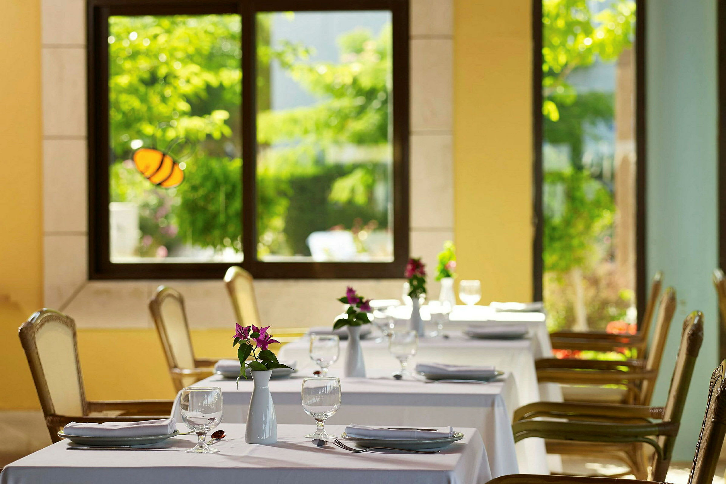 Restaurant med dækkede borde og blomster i en lys atmosfære. (AI-genereret tekst)