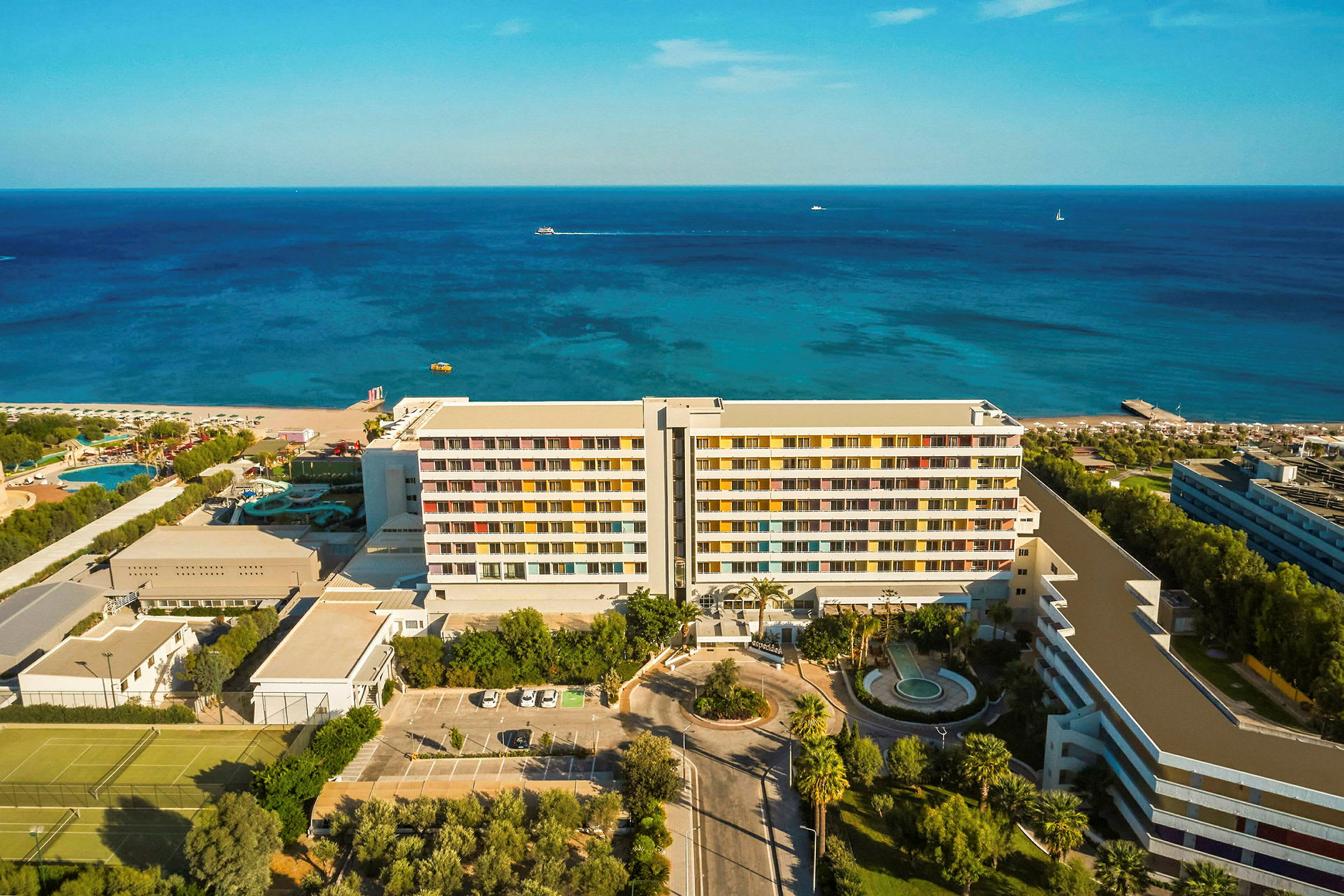 Luftudsigt over et hotel ved kysten med hav og strand i baggrunden. (AI-genereret tekst)