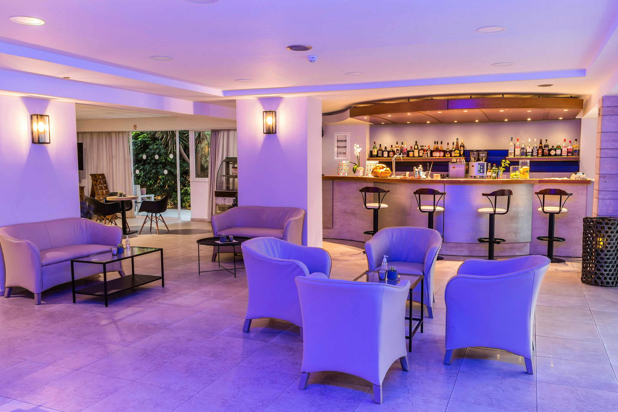 En hotelbar med siddeområder og moderne møbler, belyst af lilla loftsbelysning. (AI-genereret tekst)