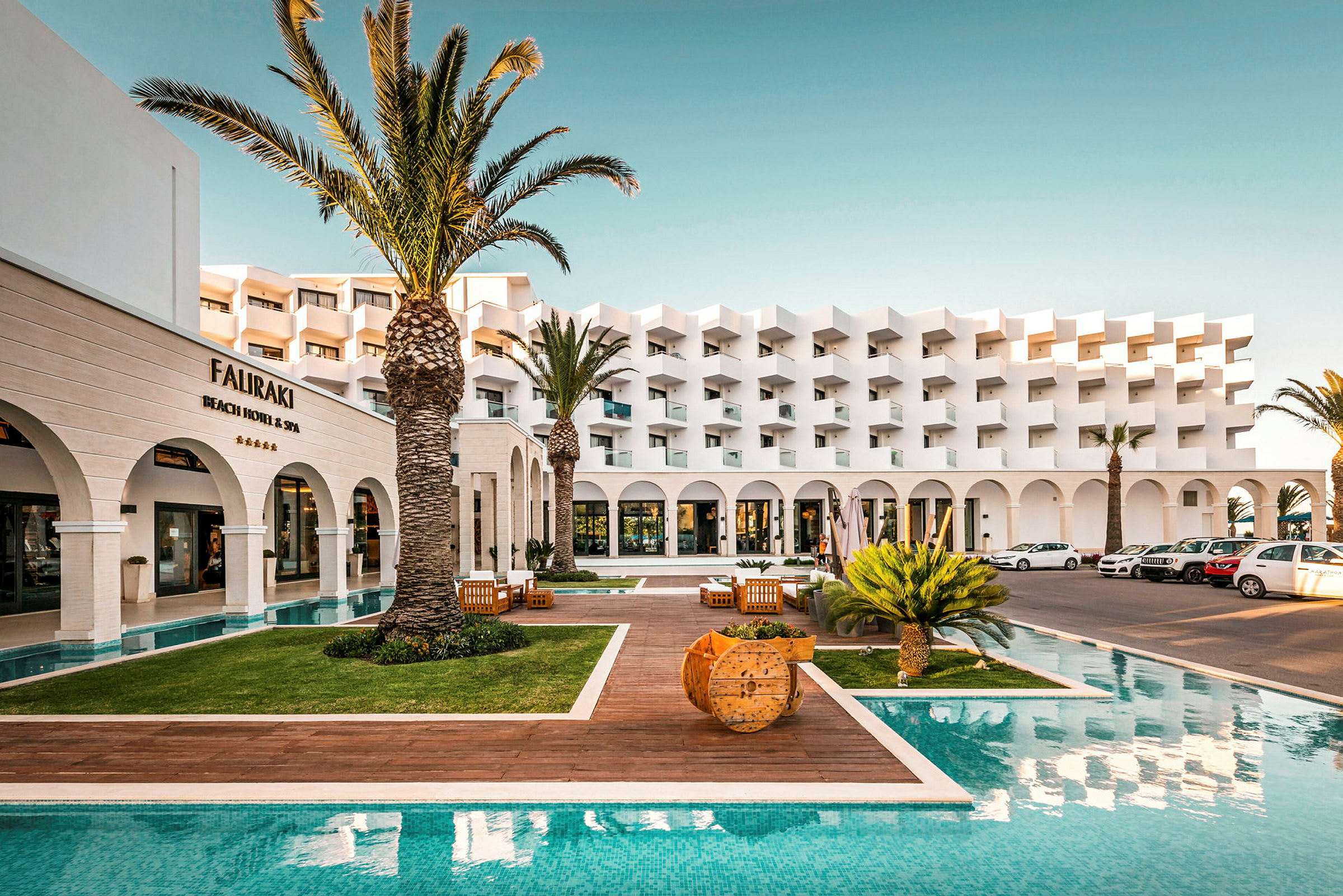 Hotelfacade med pool og palmer. (AI-genereret tekst)