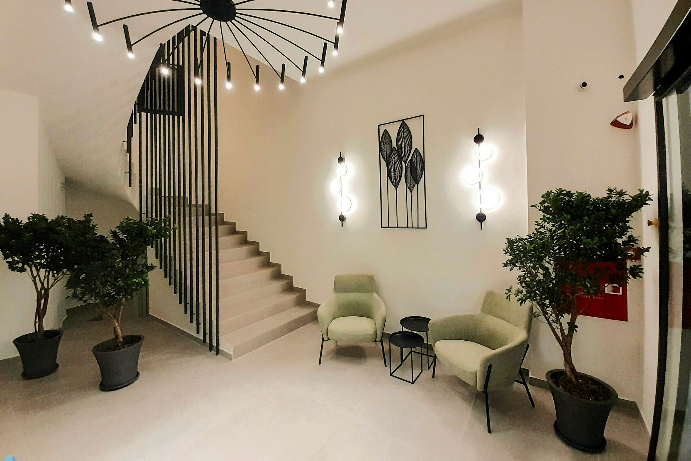 Moderne lounge med grønne lænestole, små borde og planteudsmykning. (AI-genereret tekst)
