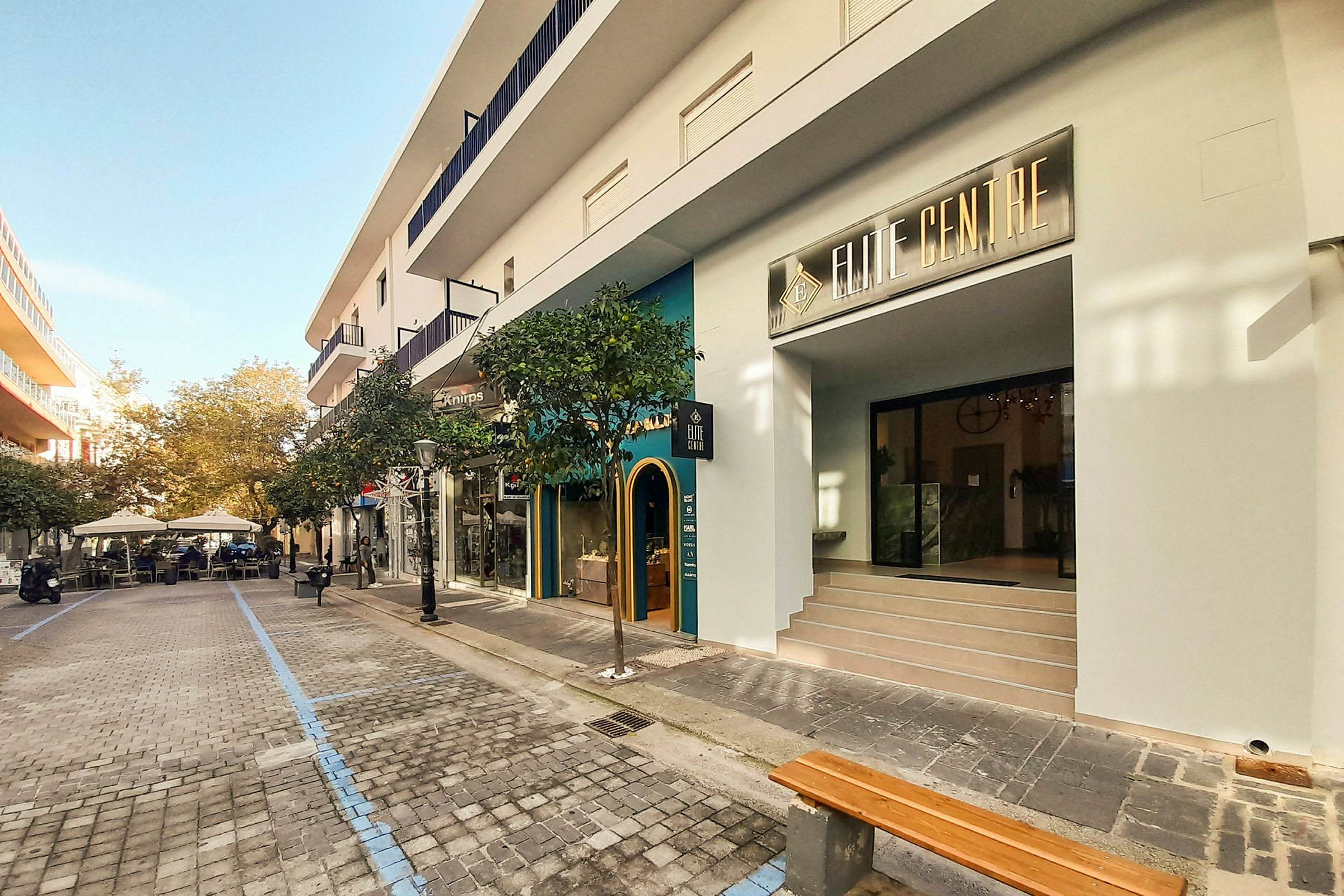 Et gademotiv med butikker og caféer langs en brolagt promenade. (AI-genereret tekst)