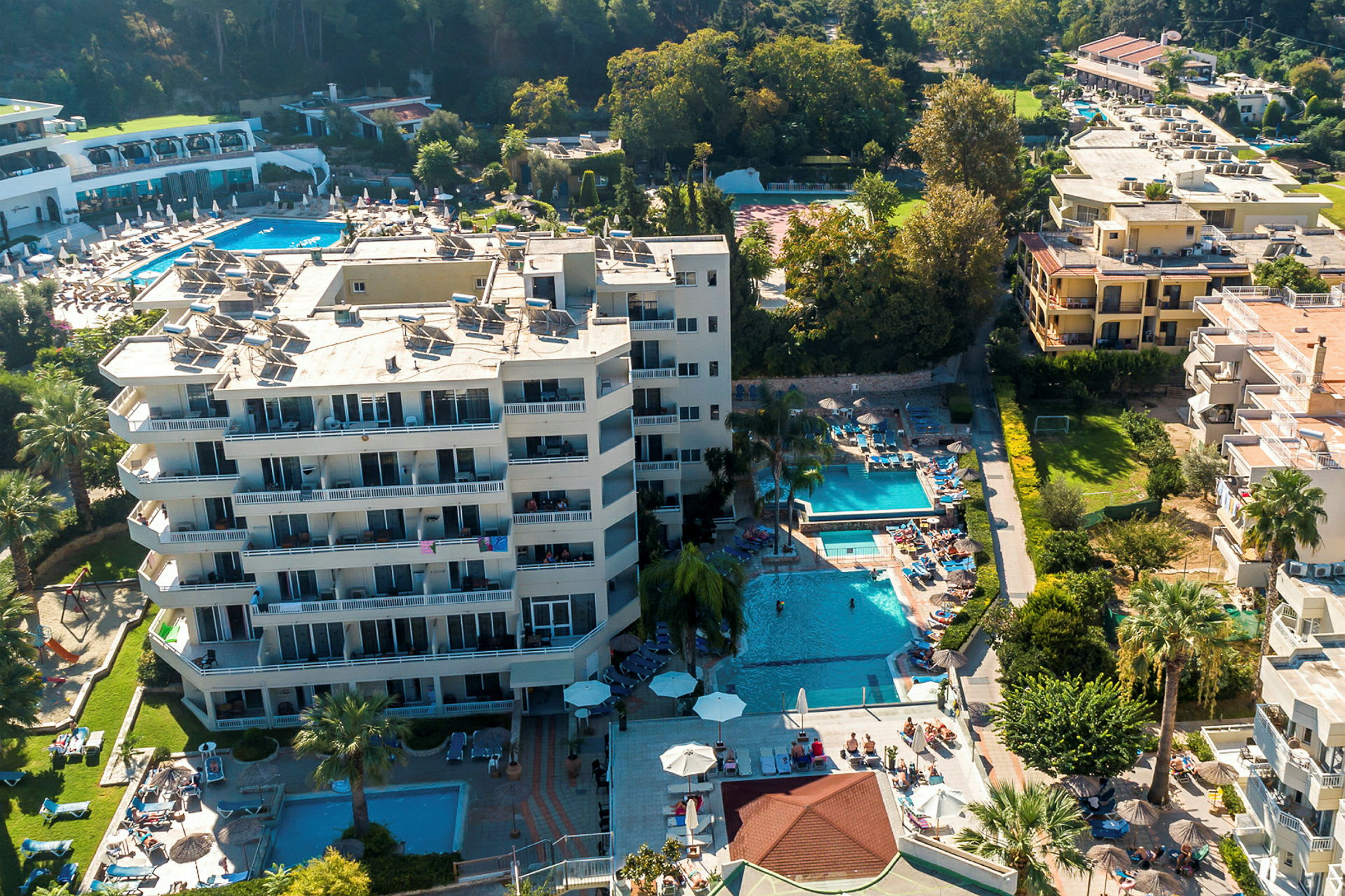 Luftfoto af hotelområde med swimmingpools og liggestole. (AI-genereret tekst)