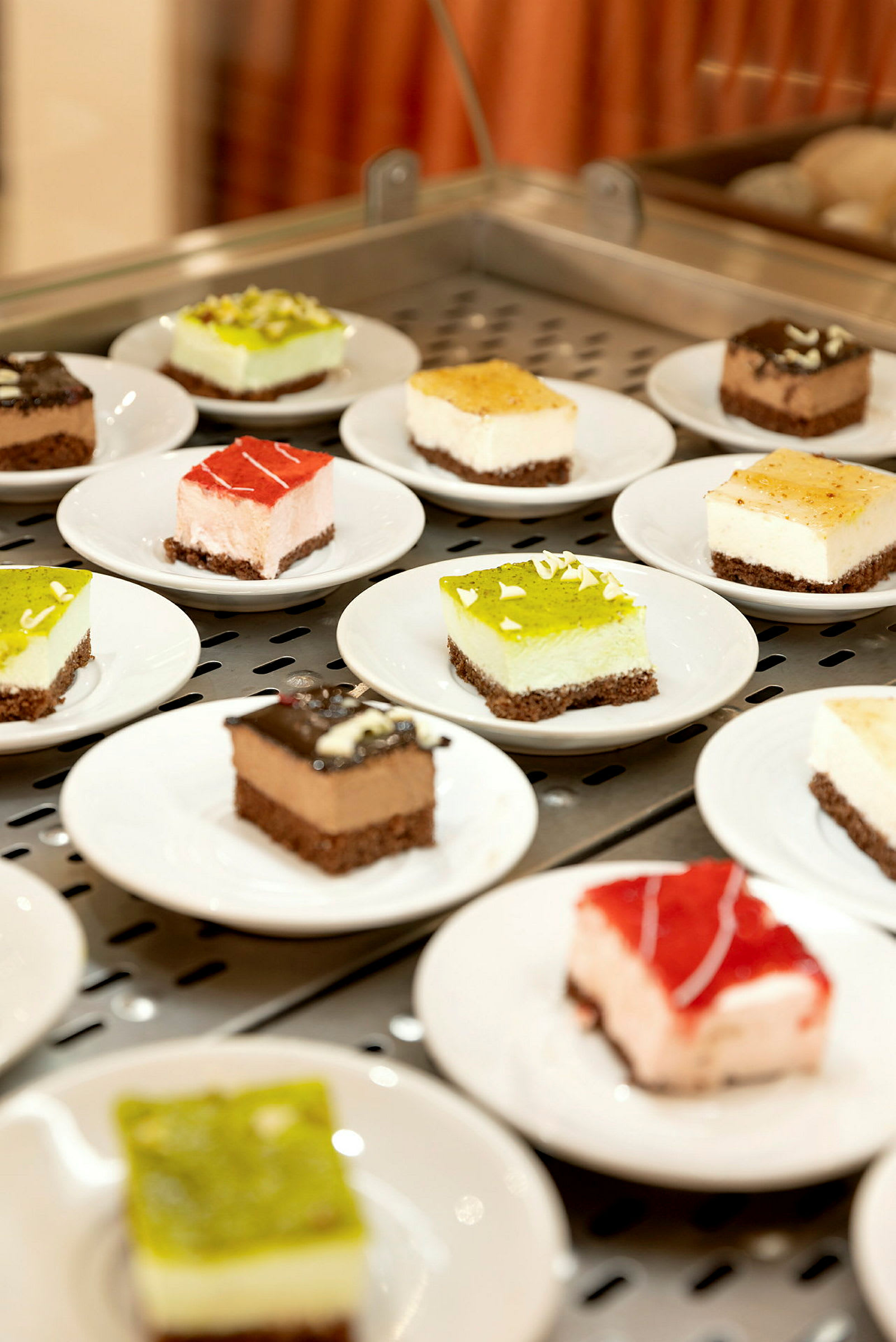 Flere små desserter på hvide tallerkener, præsenteret på en serveringsflade. (AI-genereret tekst)