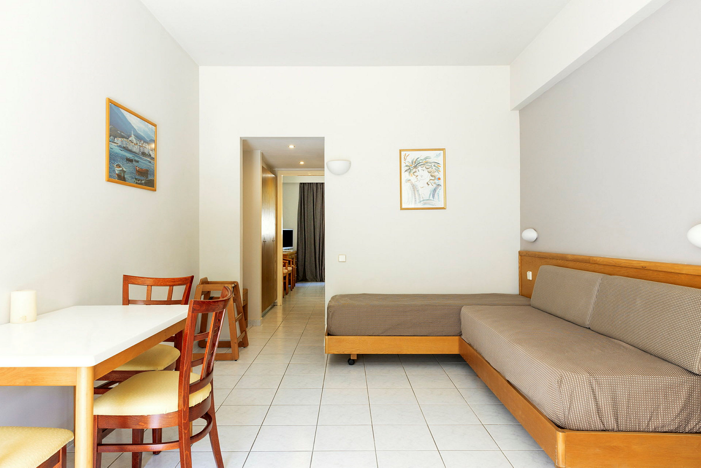 Billede af et hotelværelse med et bord, stole, en sofa og udsigt mod en gang. (AI-genereret tekst)