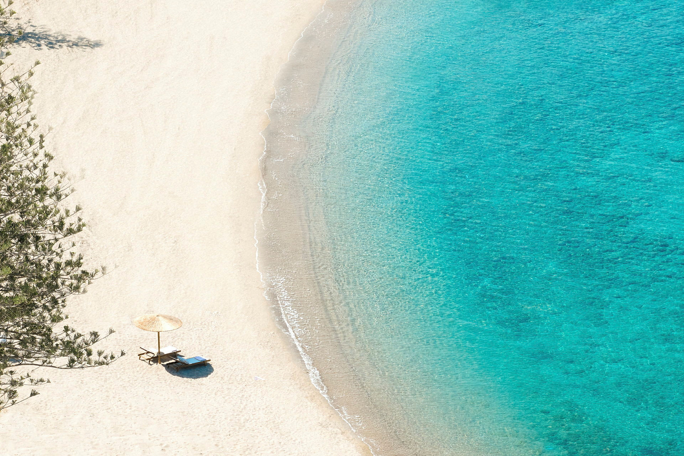 Strand med parasol og liggestole ved vandkanten. (AI-genereret tekst)