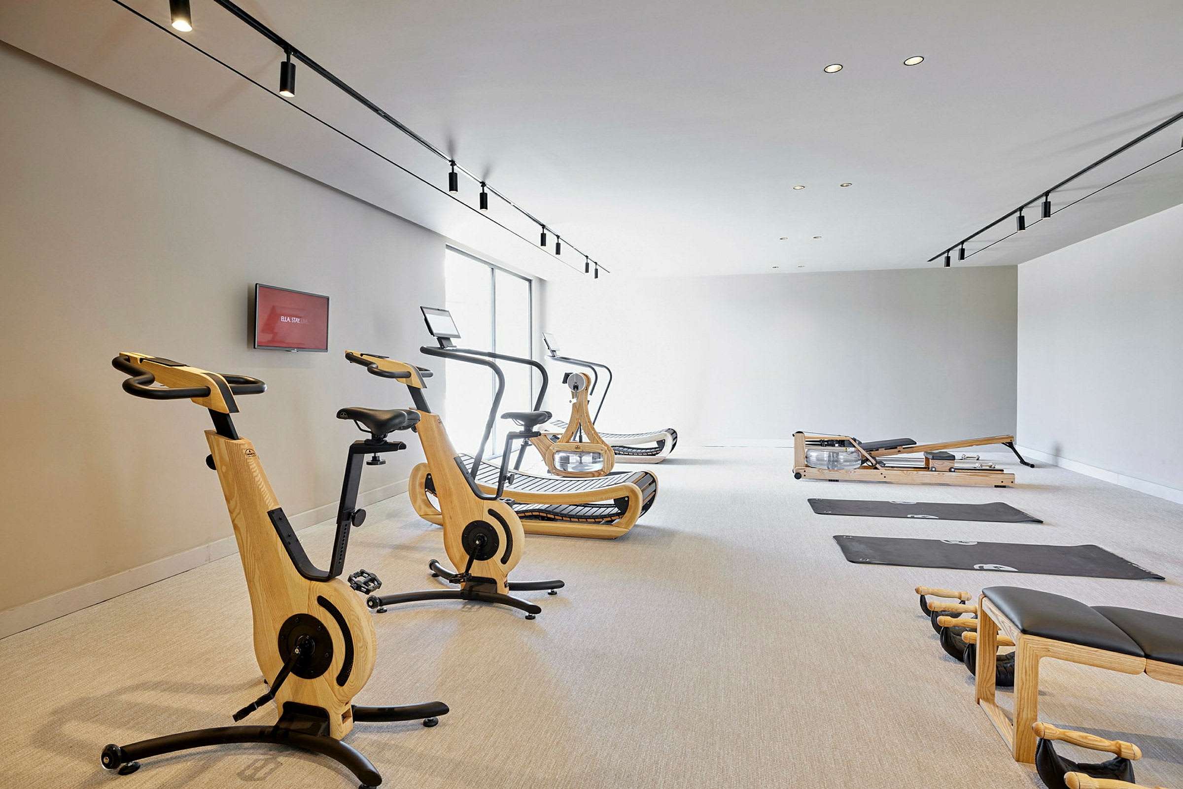 Fitnessrum med træningsudstyr, herunder motionscykler, løbebånd og måtter. (AI-genereret tekst)
