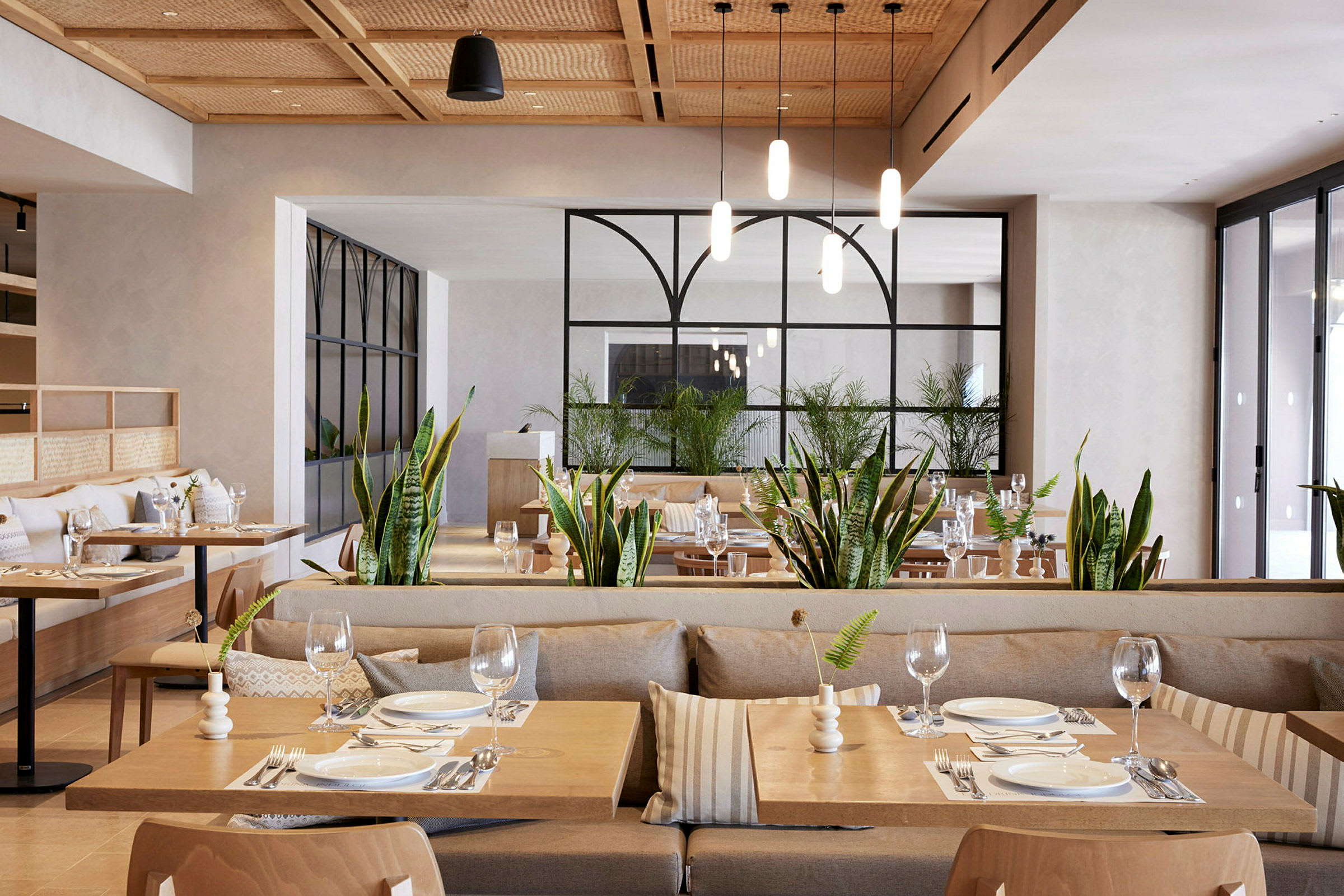 Billede af en restaurant med moderne indrettede spiseborde og grønne planter. (AI-genereret tekst)