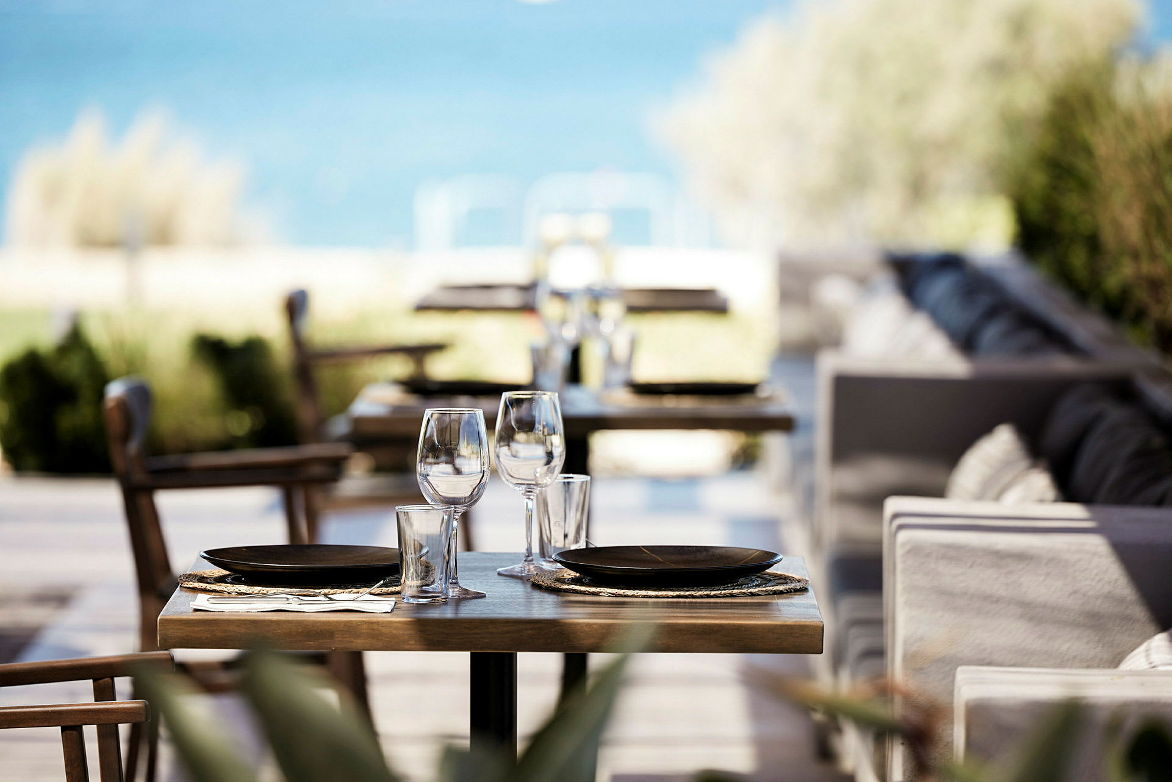Billede af et dækket bord på en restaurant med havet i baggrunden. (AI-genereret tekst)