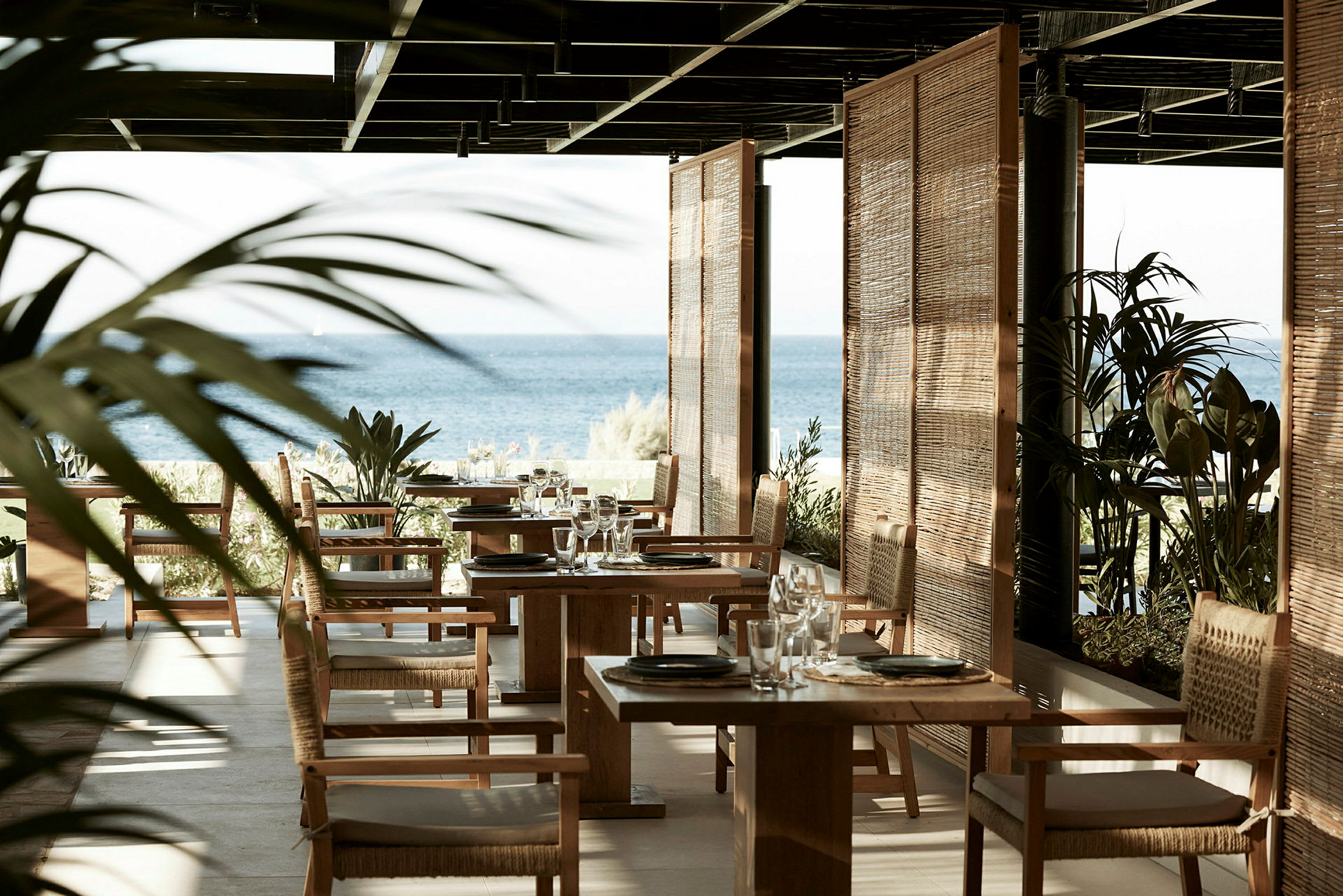 Restaurant med havudsigt, træstole og borde. (AI-genereret tekst)