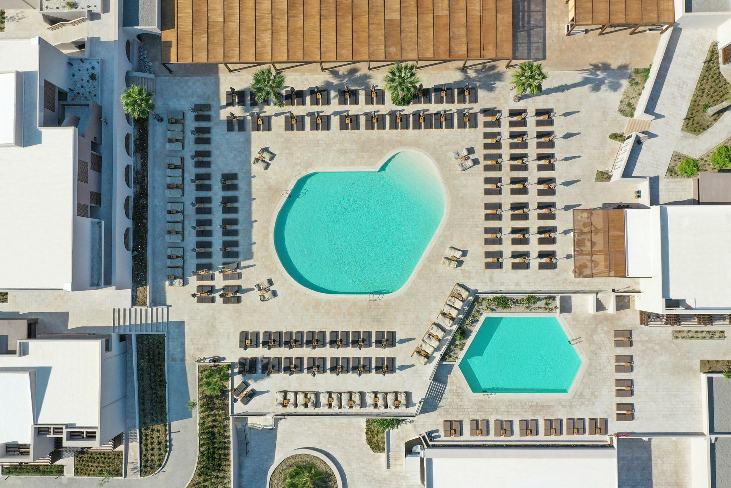 Luftfoto af poolområde ved et hotel med solsenge omkring. (AI-genereret tekst)