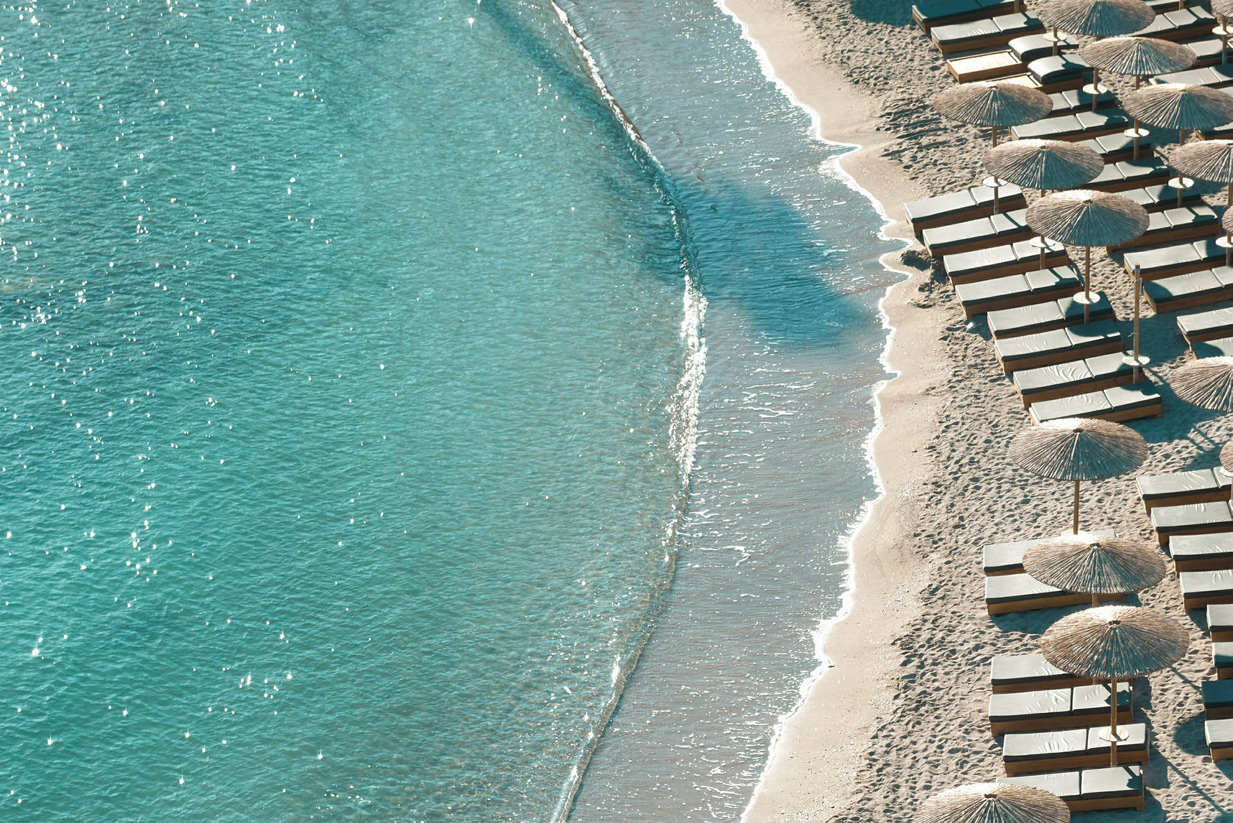 Strand ved havet med parasoller og solsenge. (AI-genereret tekst)