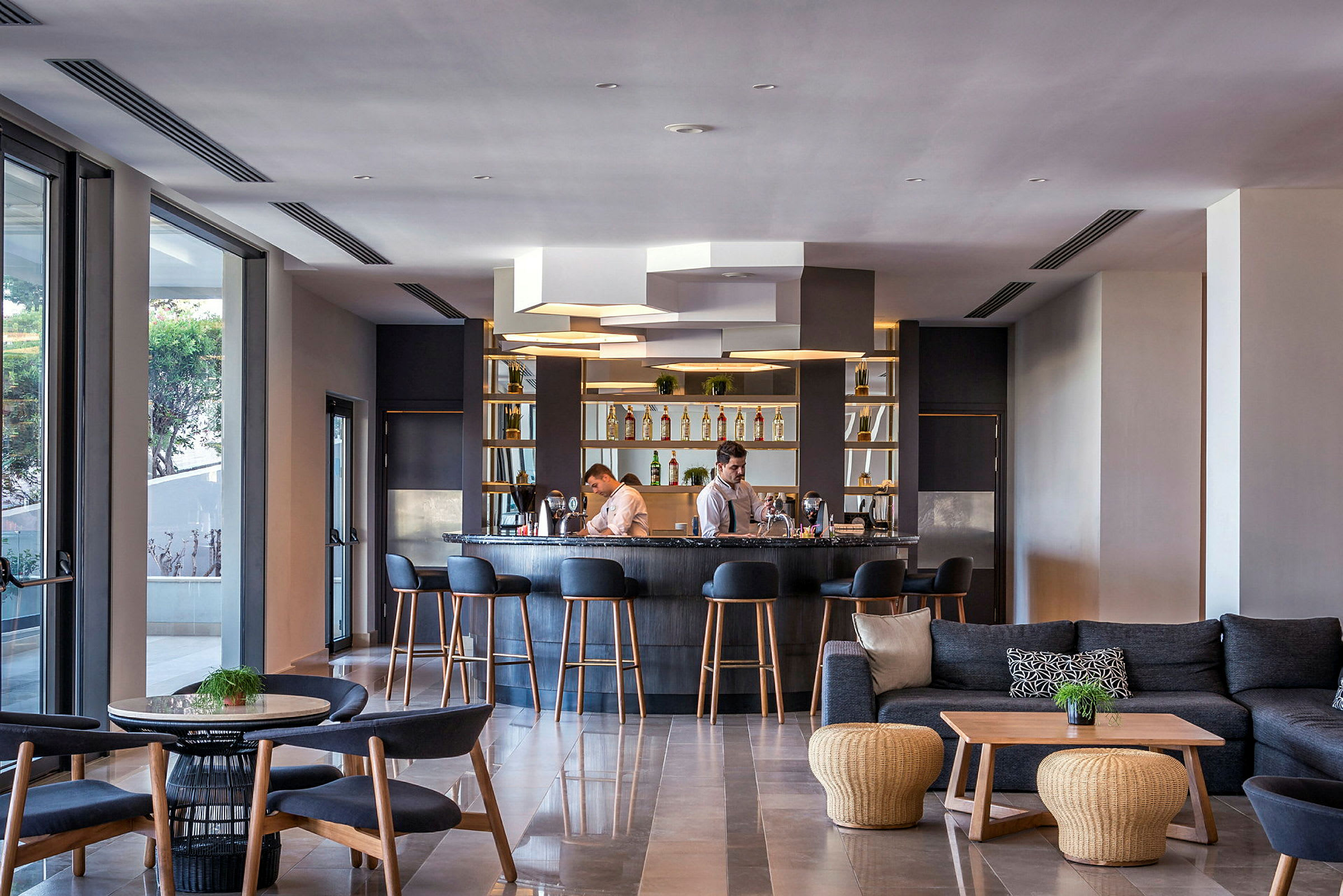 Hotelbar med stole og sofaer, samt personale bag disken. (AI-genereret tekst)