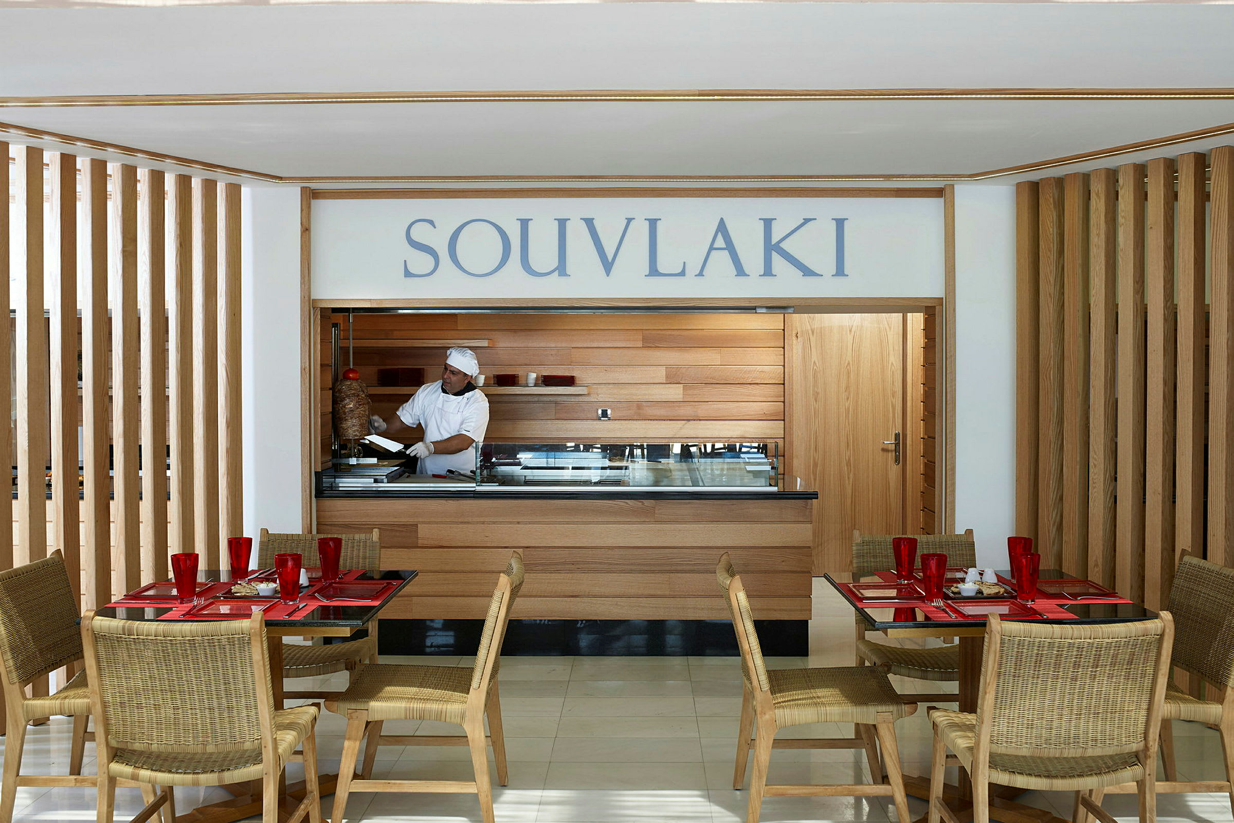 En restaurant med en souvlaki-servering. Bord og stole er placeret i forgrunden. (AI-genereret tekst)