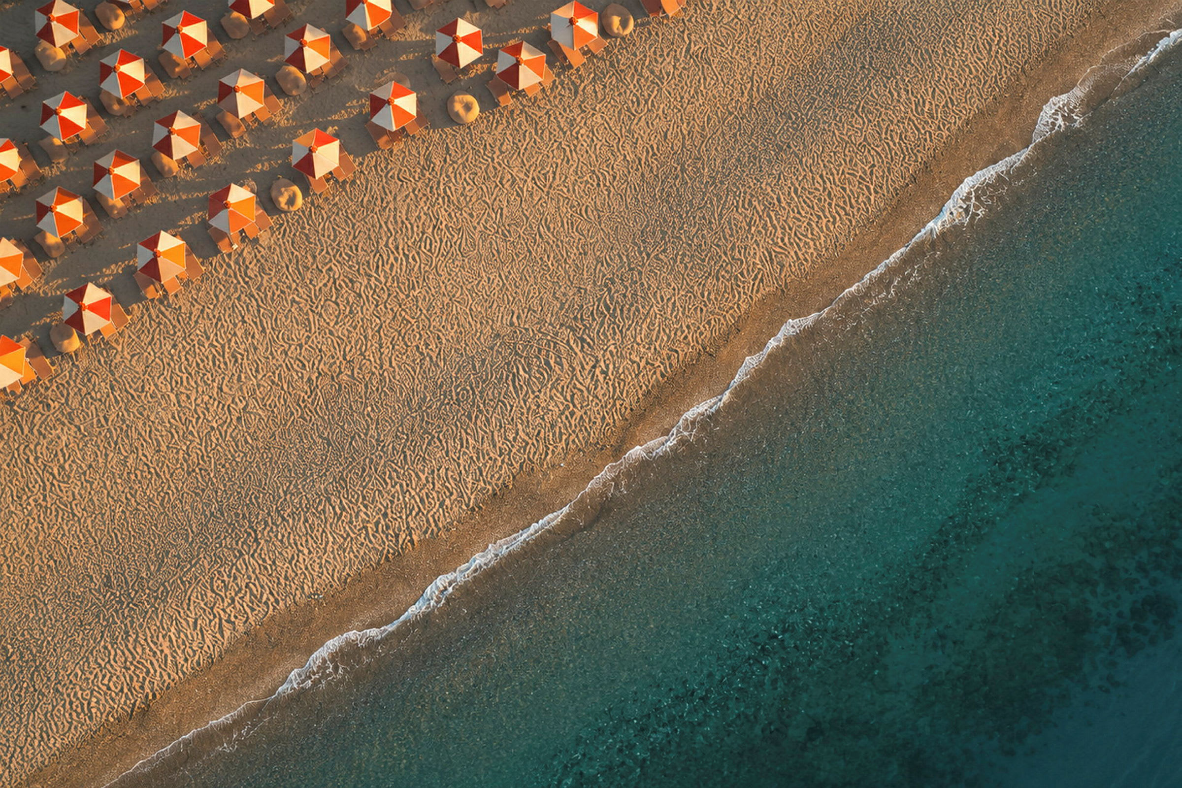 Strand med orange parasoller og blåt hav. (AI-genereret tekst)