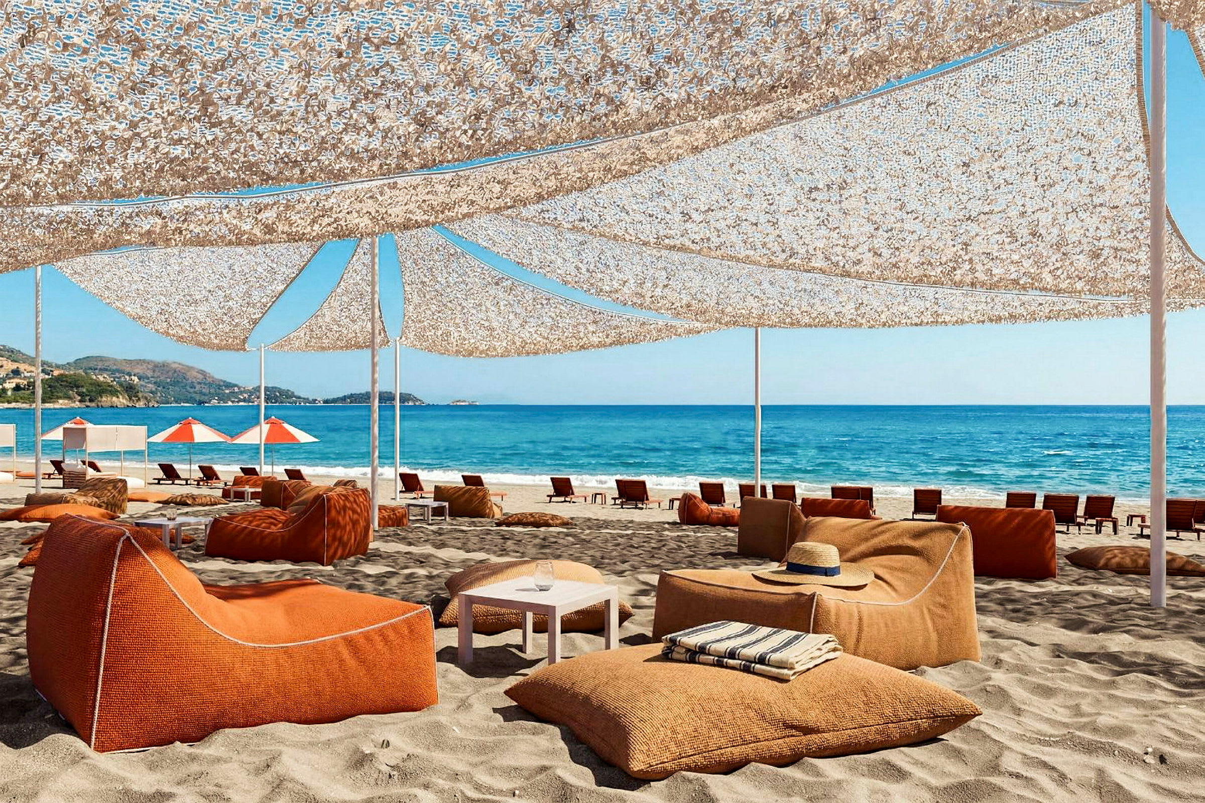 Strand med orange siddepladser under en solafskærmning. Hav og blå himmel i baggrunden. (AI-genereret tekst)