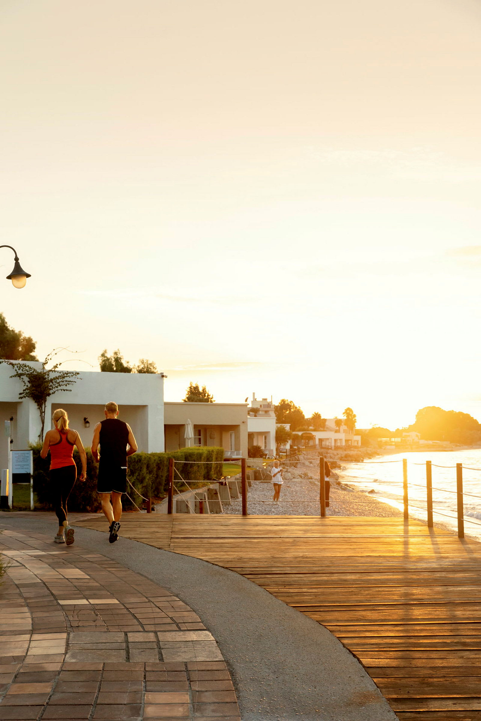 To personer jogger på en strandpromenade i solnedgangen. (AI-genereret tekst)