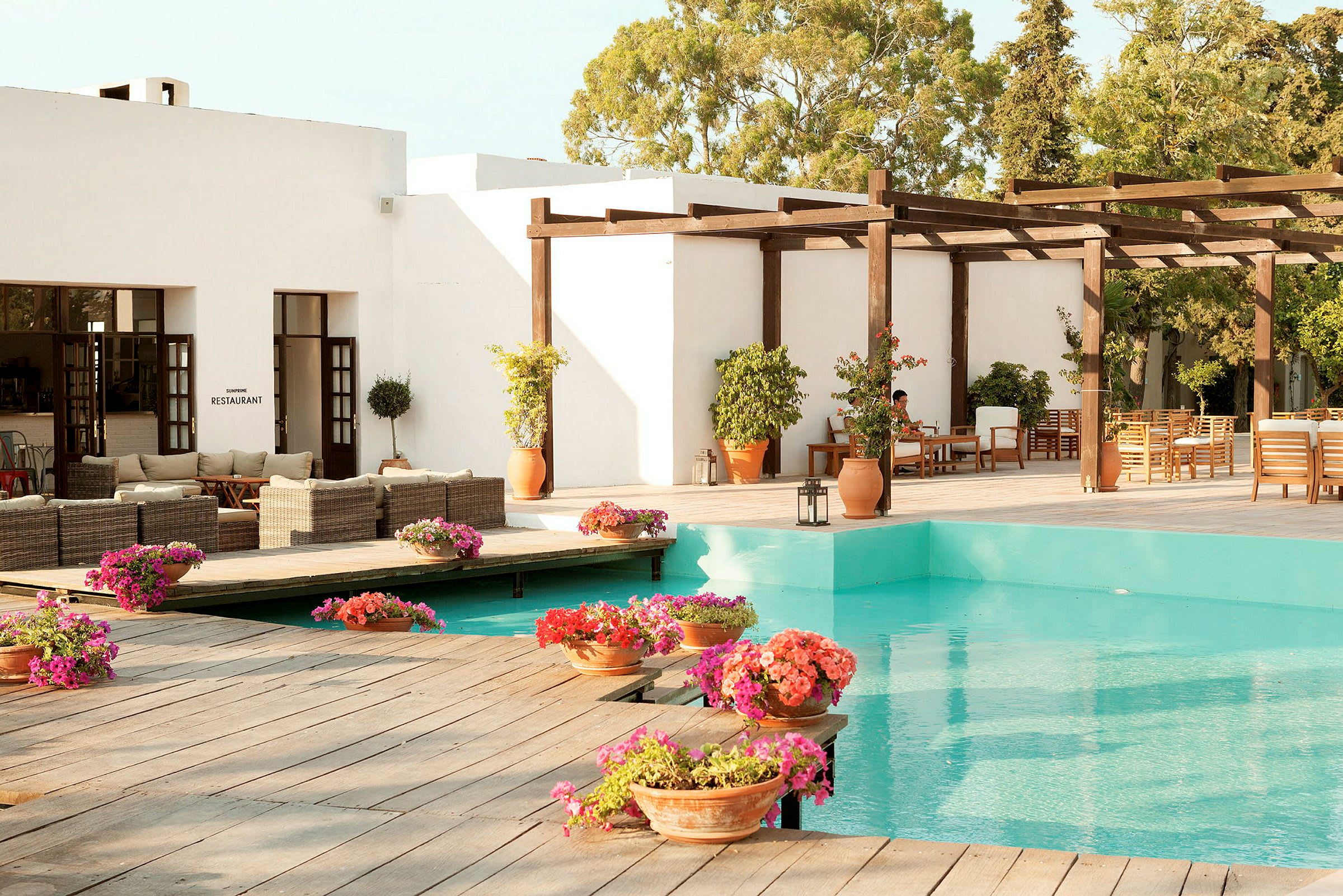 Billede af en terrasse med pool, blomster og siddeområder. (AI-genereret tekst)
