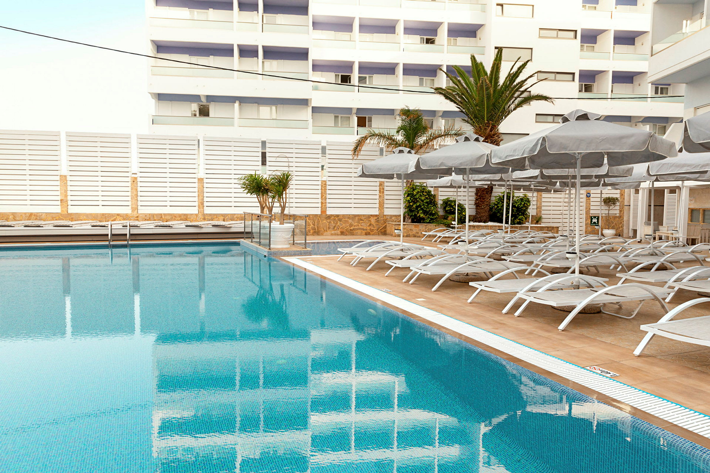 Udendørs pool med liggestole og parasoller i en moderne hotelmiljø. (AI-genereret tekst)