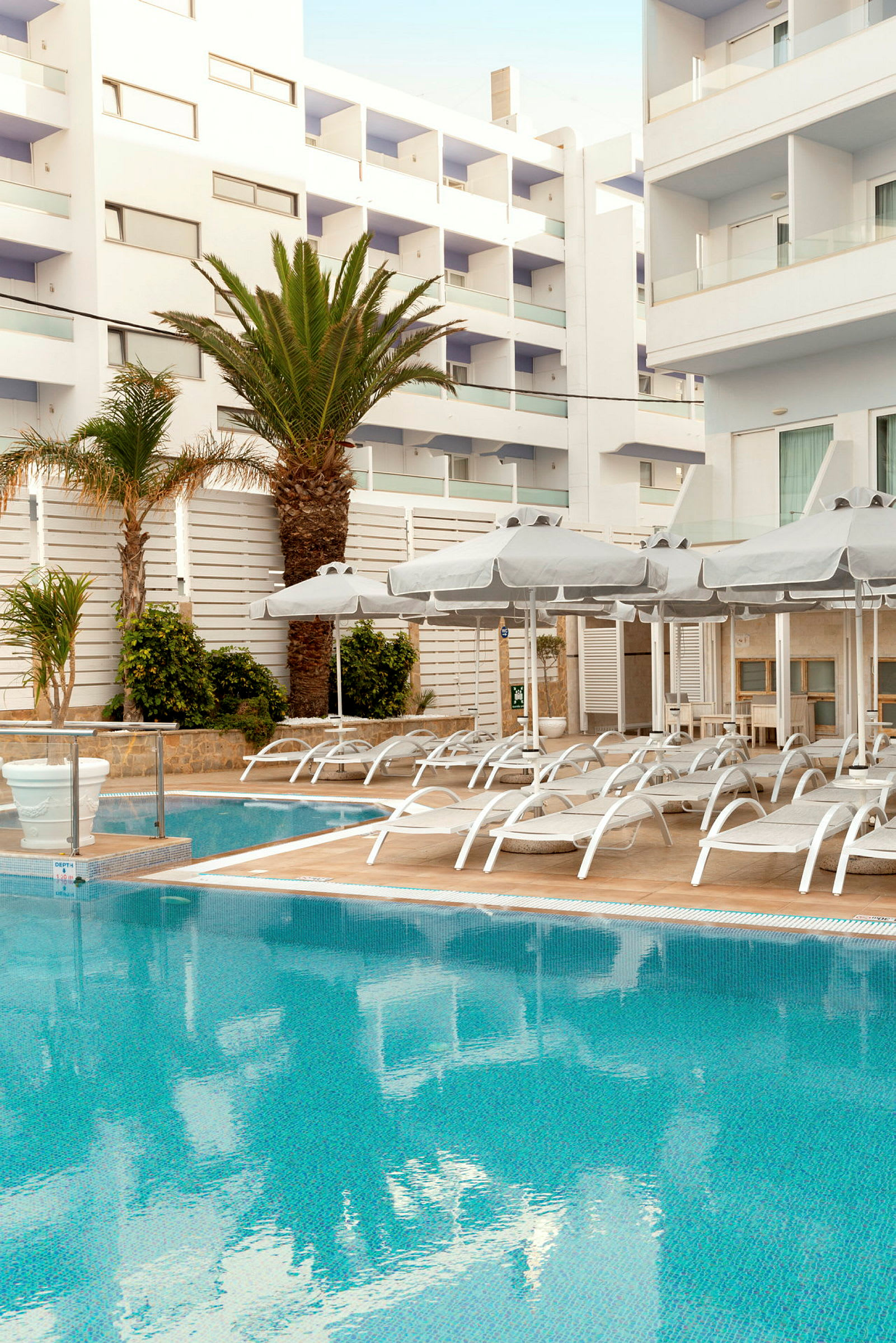 Udendørsområde med pool, liggestole og parasoller ved et hotel. (AI-genereret tekst)