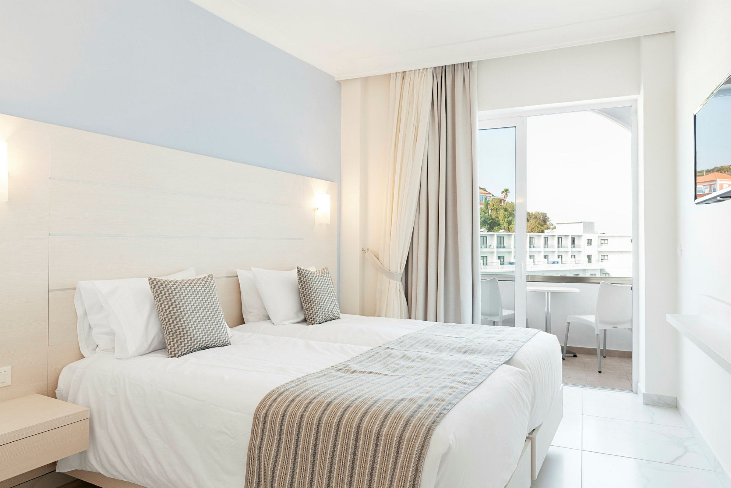 Hotelværelse med to enkeltsenge og altan. (AI-genereret tekst)